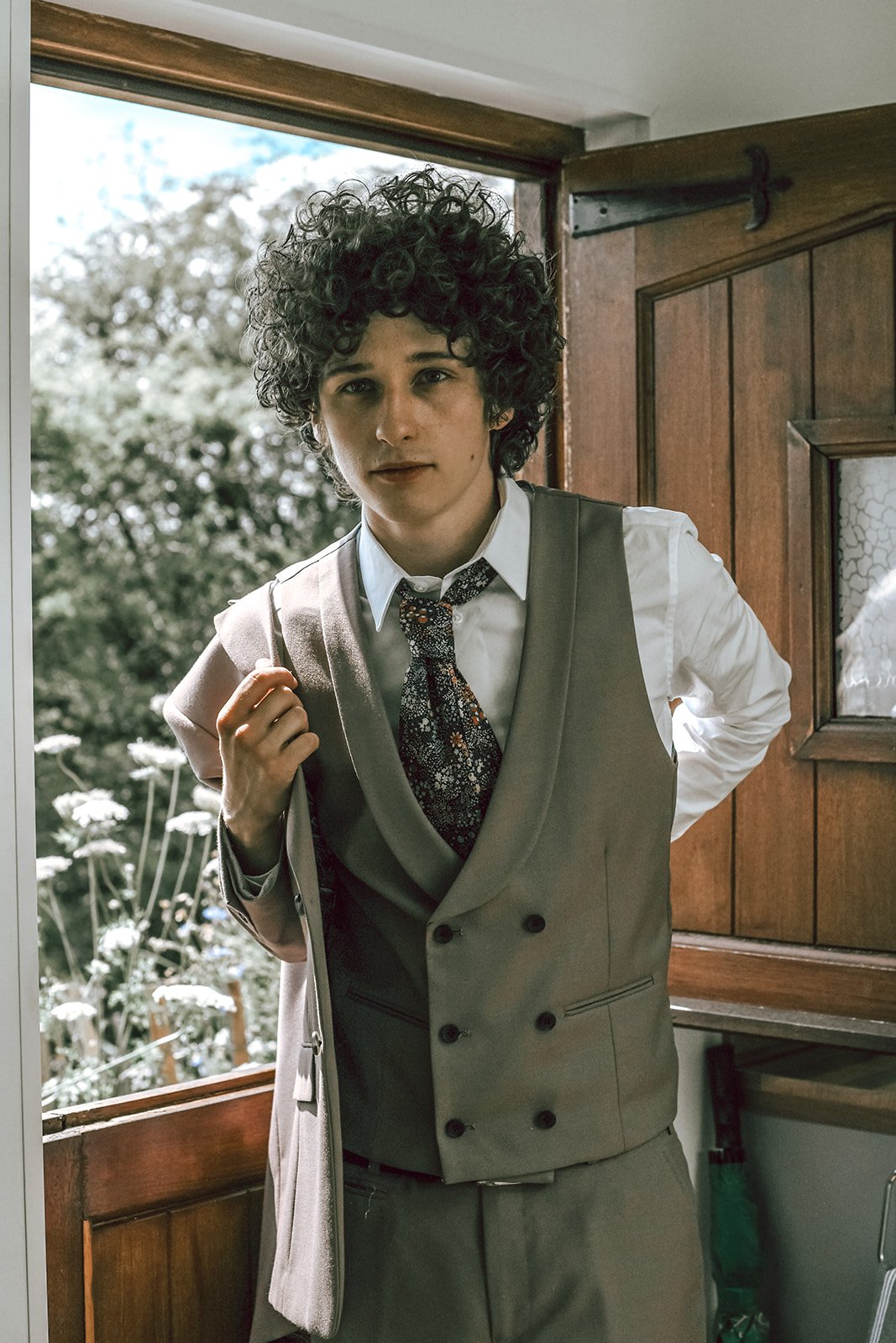 a curly haired groom wearing a tweed suit
