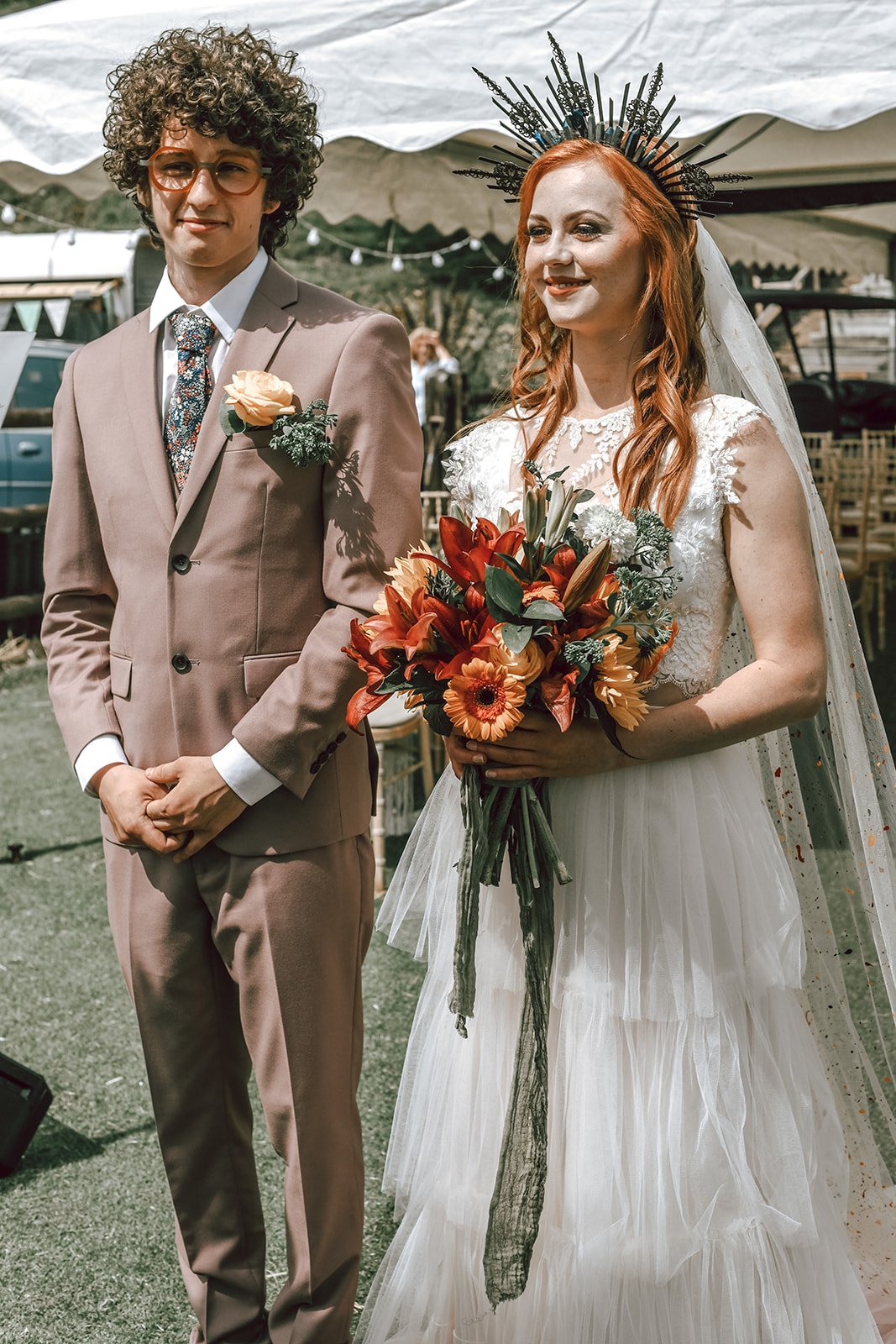 a groom wearing glasses stands next to his red haired bride
