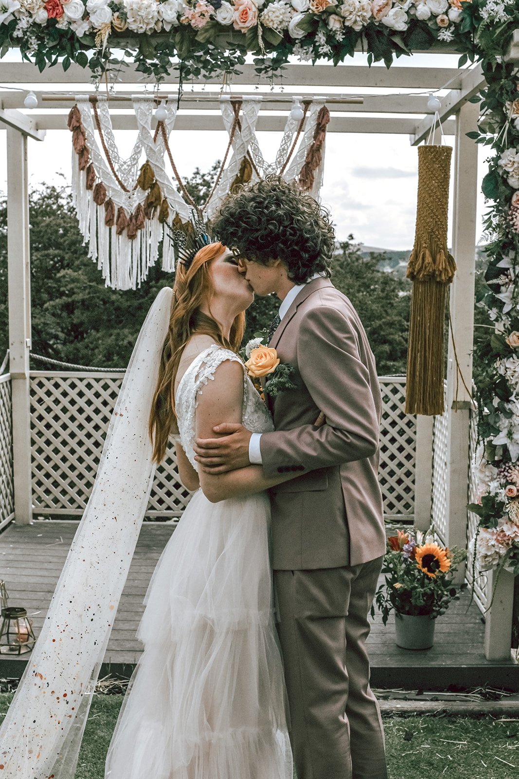 bride and groom kissing in front of a bohemian macrame backdrop