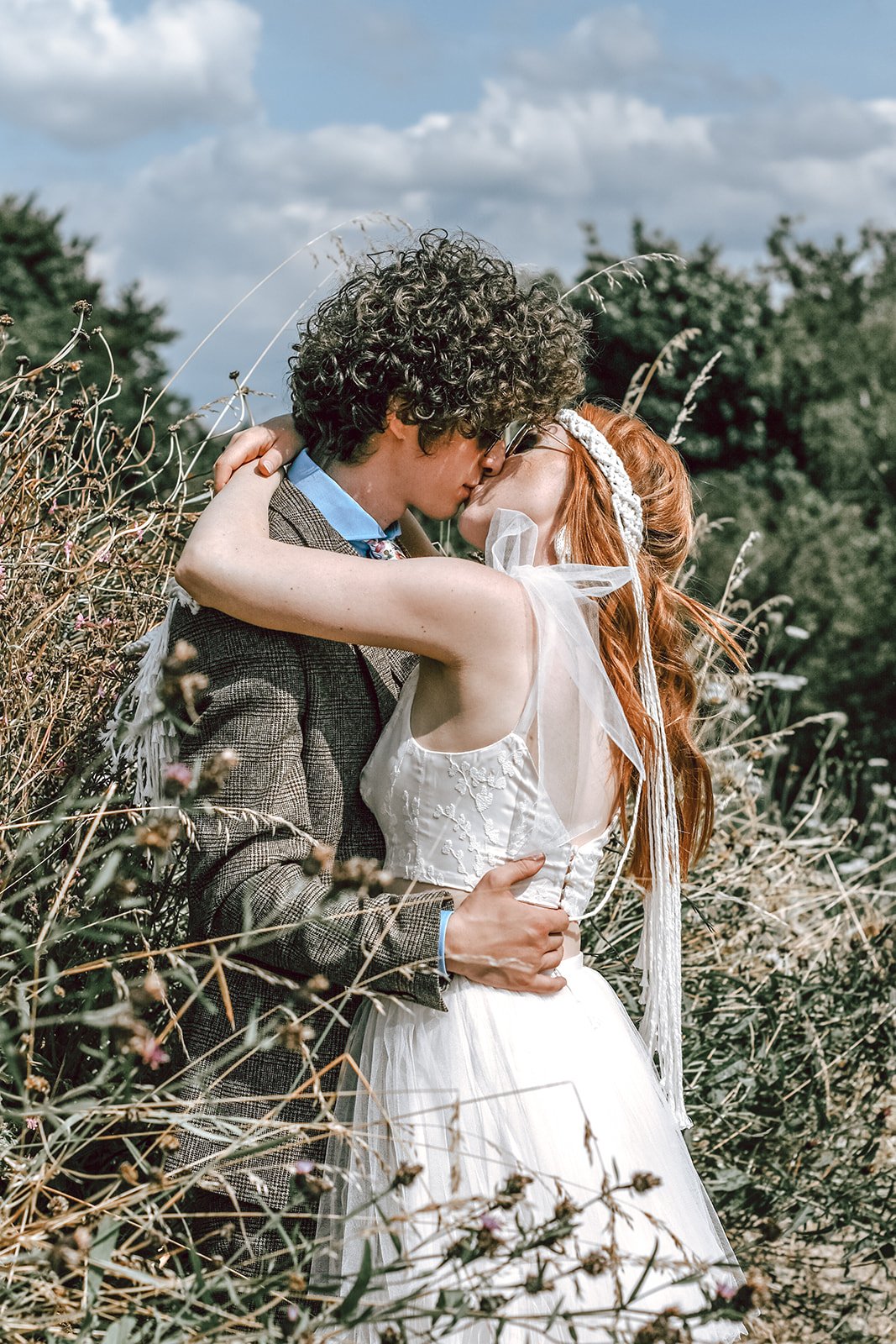 a newlywed couple kissing in a field