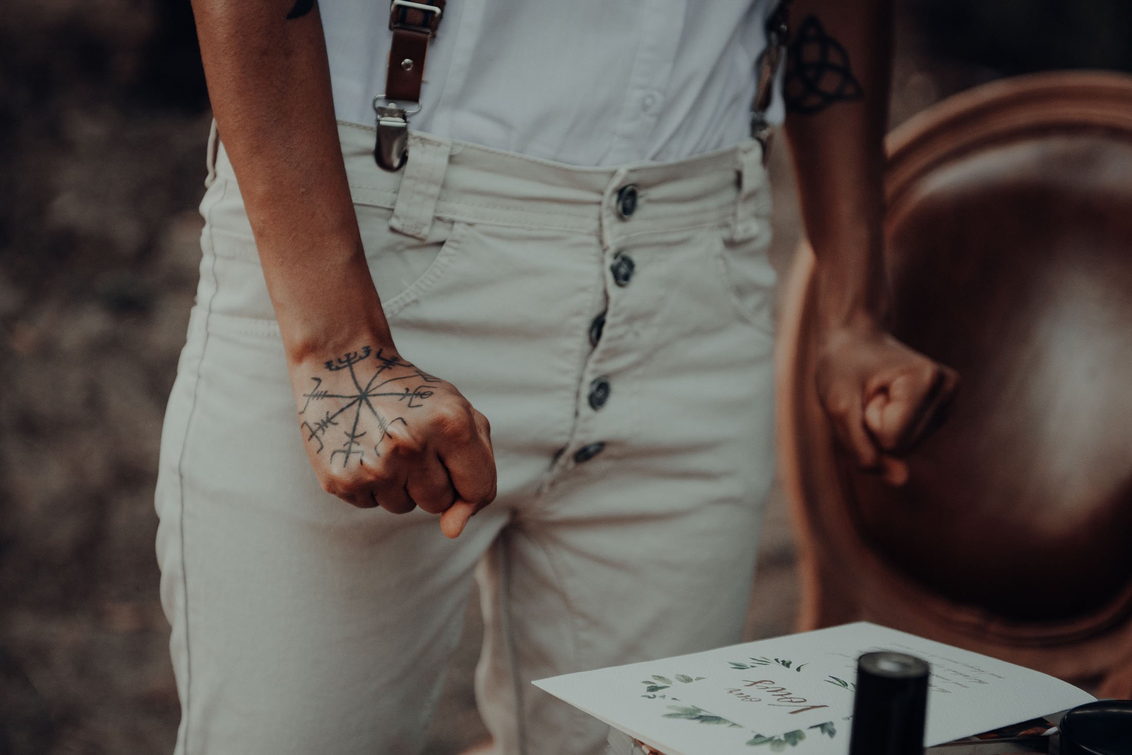  The bride clenching her tattooed fists, over a book that reads ‘our  vows’. 