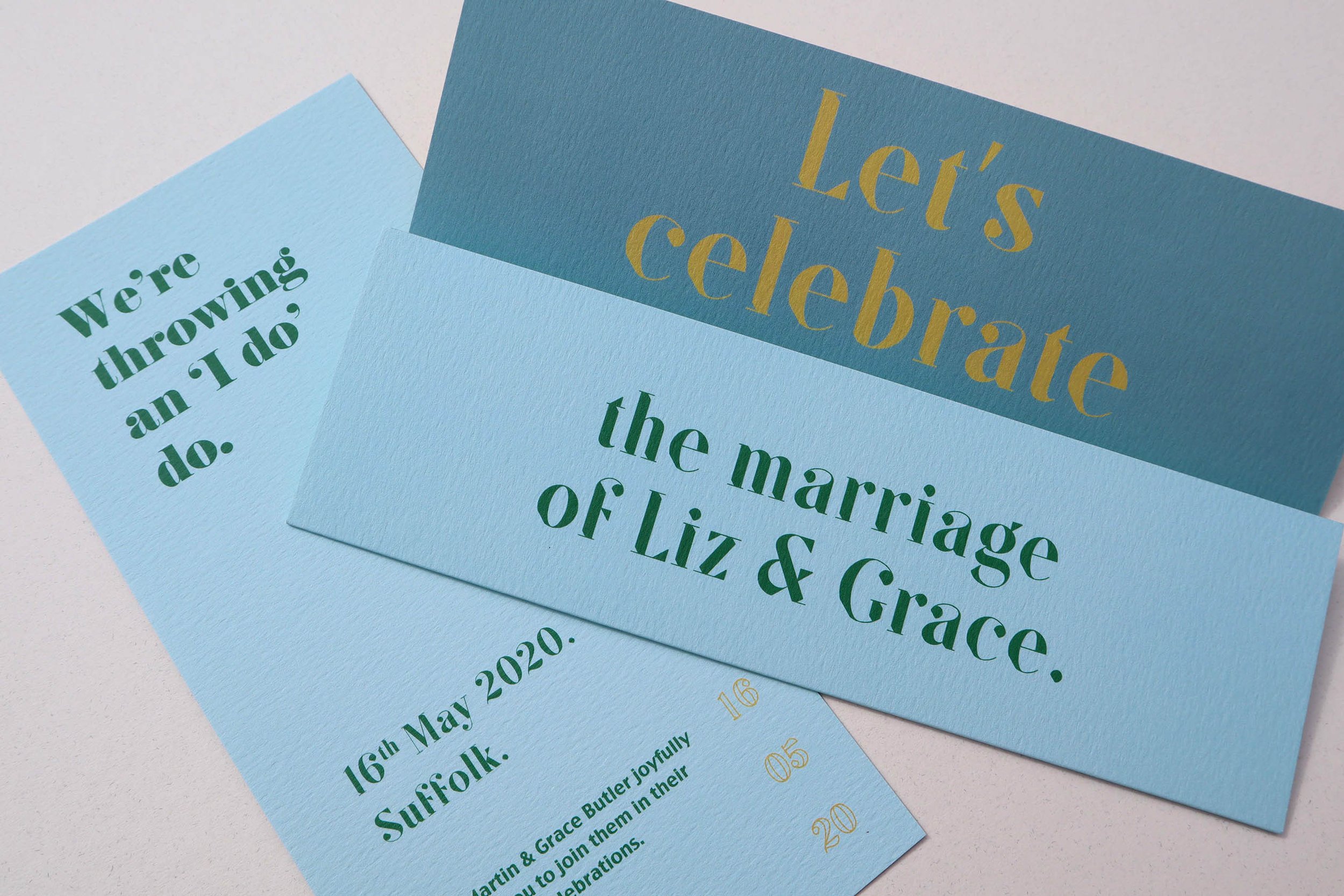  Two-tone blue wedding stationery with bold gold type that says ‘‘et’s celebrate’. 