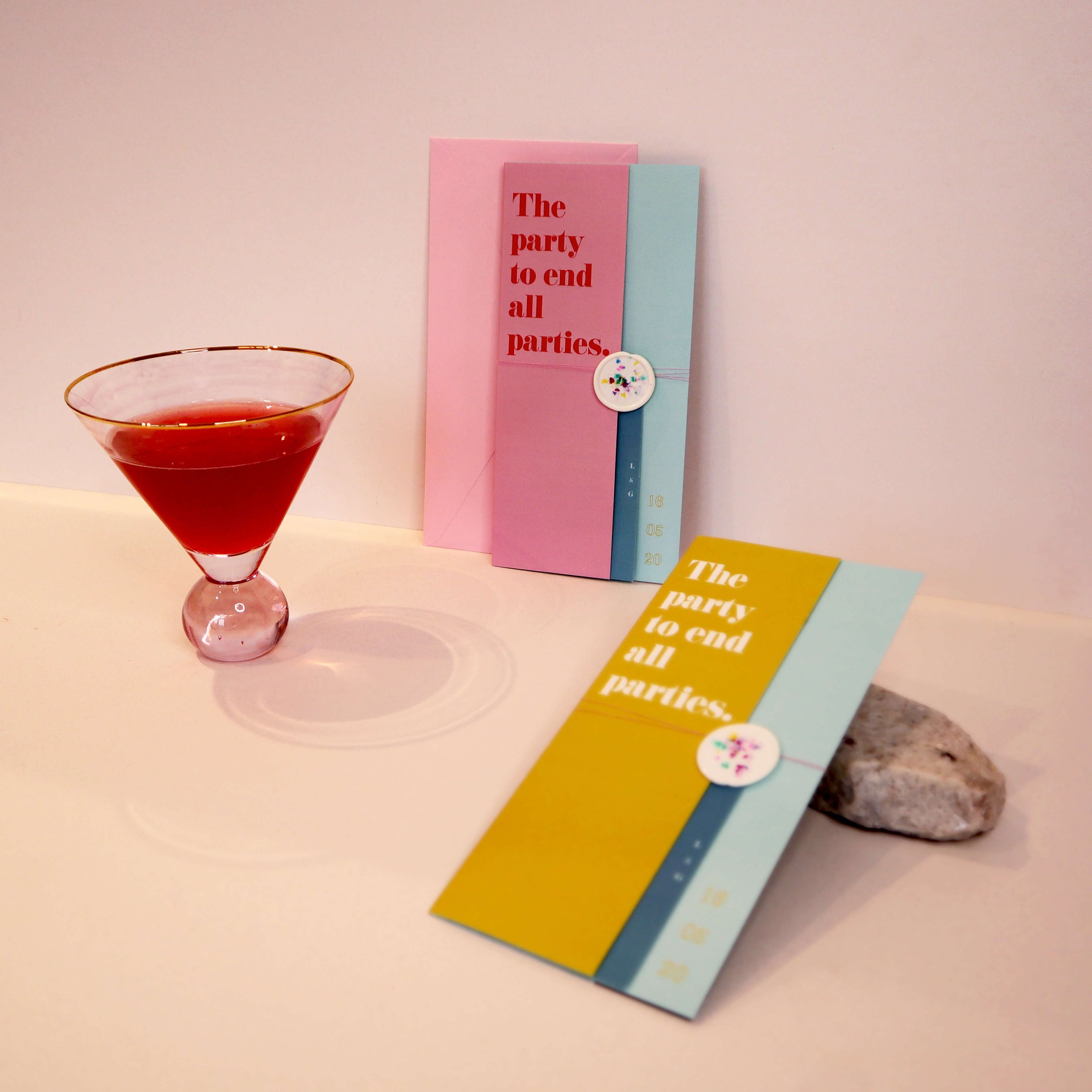  A very cool shot of some contemporary, colourful wedding stationery and a red cocktail in a triangular glass. 