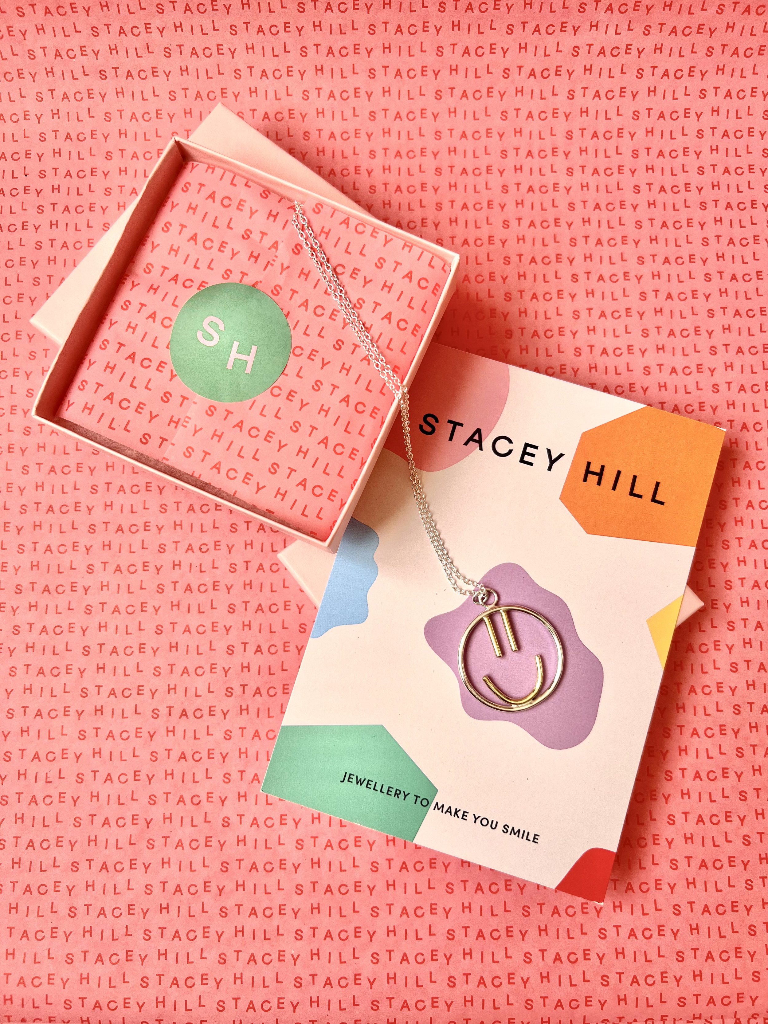  A handmade smiley necklace styled on top of a colourful Stacey Hill flyer and her pink tissue paper. 