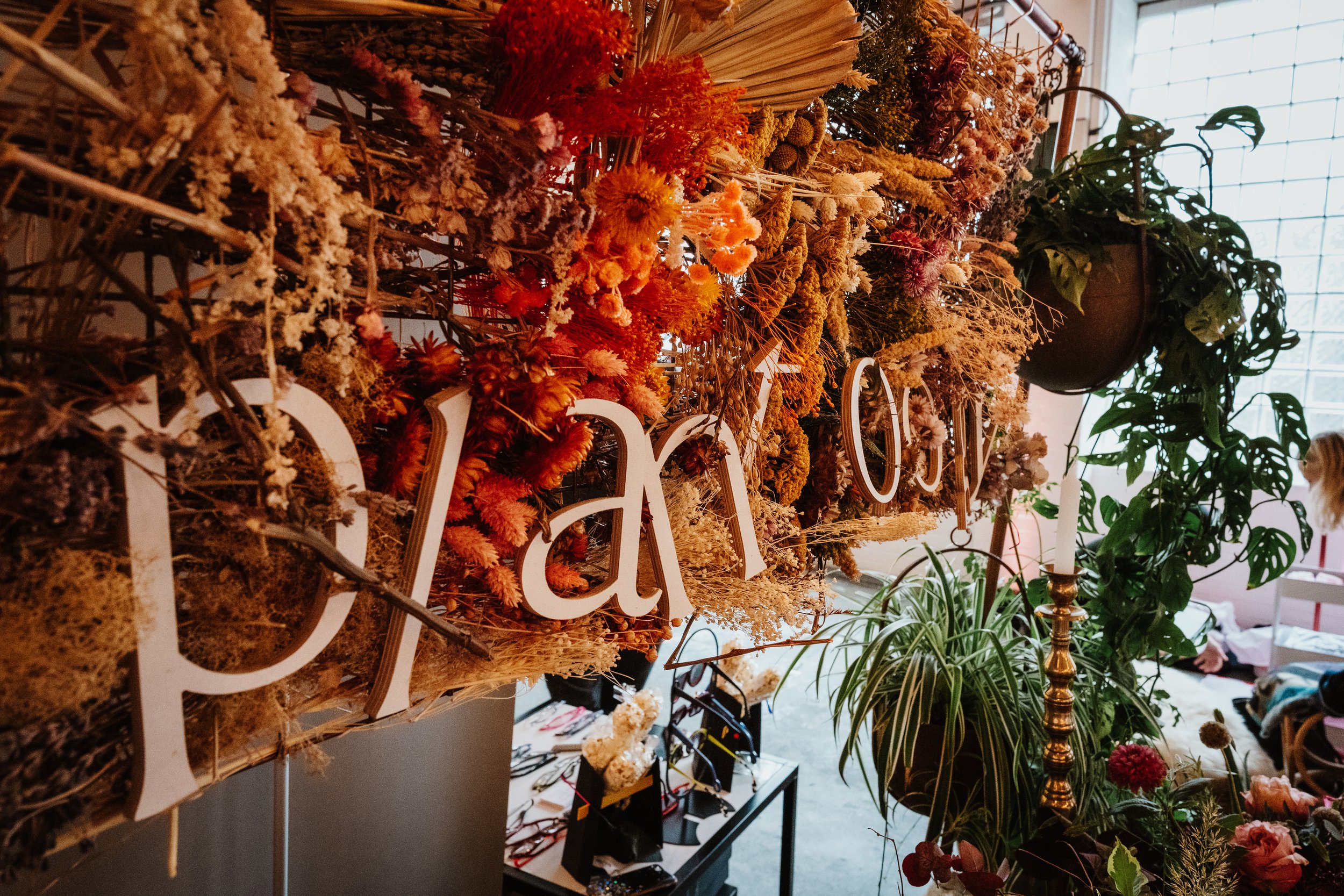  A colourful dried floral backdrop with wooden letters that spell ‘Plantology’. 