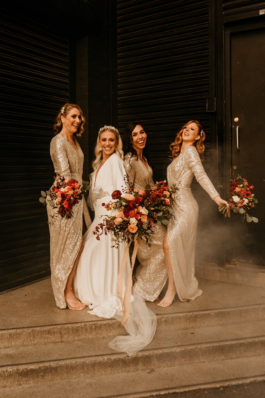  A very cool photo of a bride with her 3 bridesmaids. They are all posing in their long-sleeved, sequin dresses and showing off their matching bouquets. 