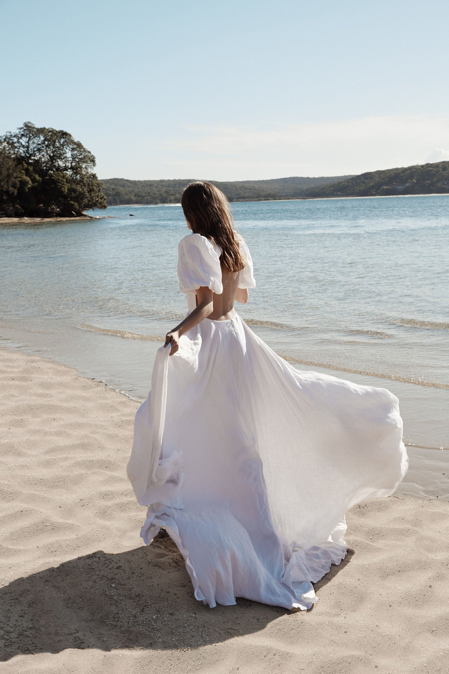  A bride running across the beach and showing off her long, floaty dress. 