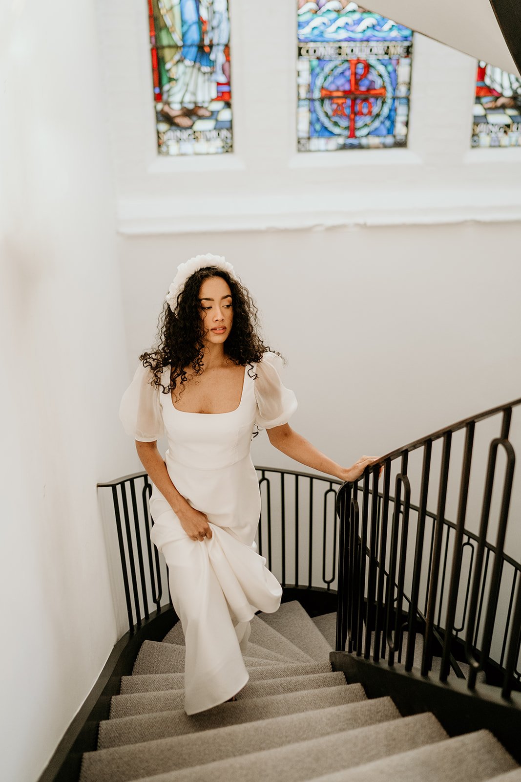  A curly haired bride wearing a simple gown and walking up some stairs at Lambeth Town Hall. 
