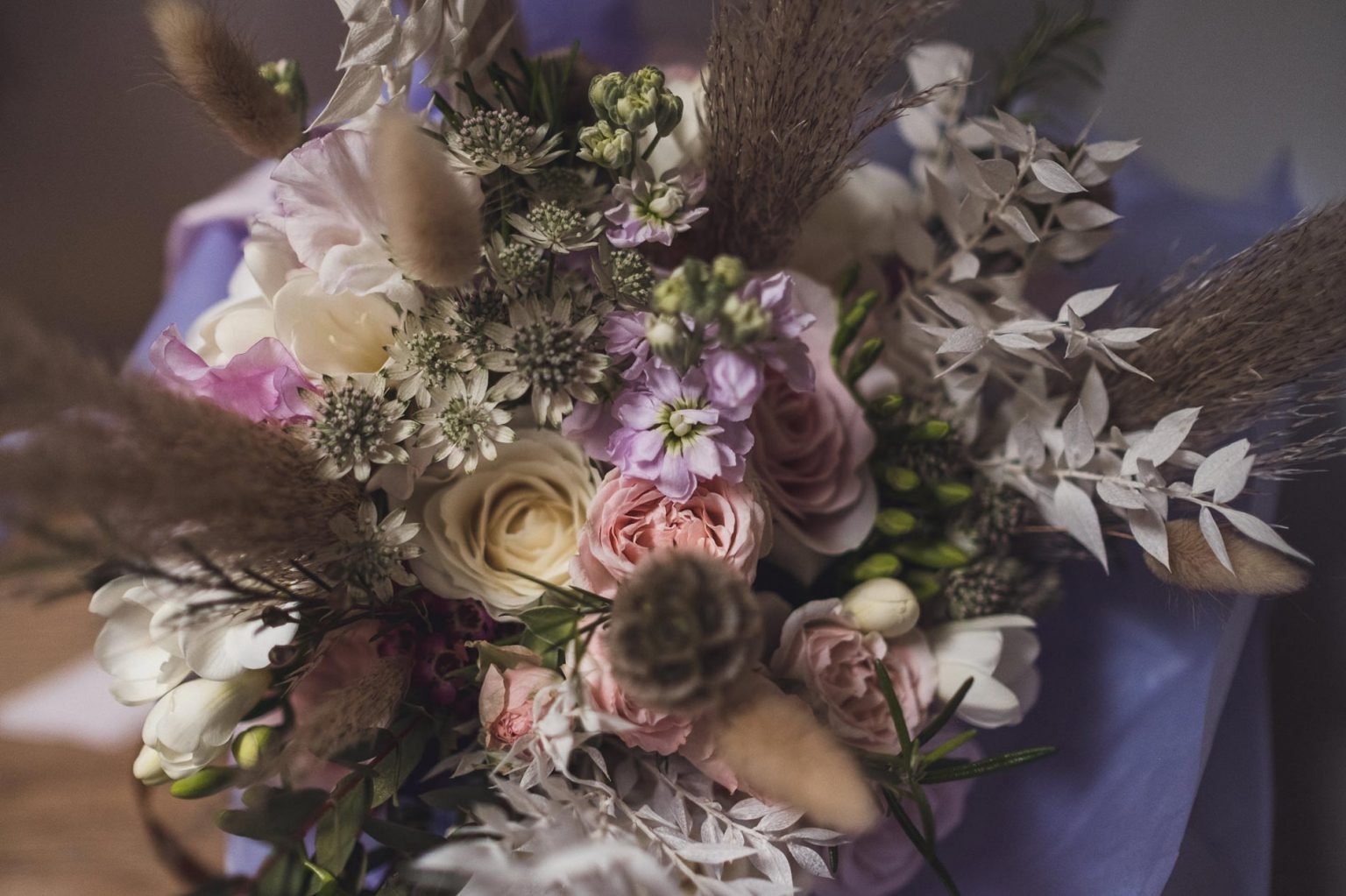  An up close image of a modern bridal bouquet. The pastel pinks and lilacs are alongside white flowers and the various textures, stems and foliage create a contemporary display.     Photo Credit: Steve Fanstone Photography 