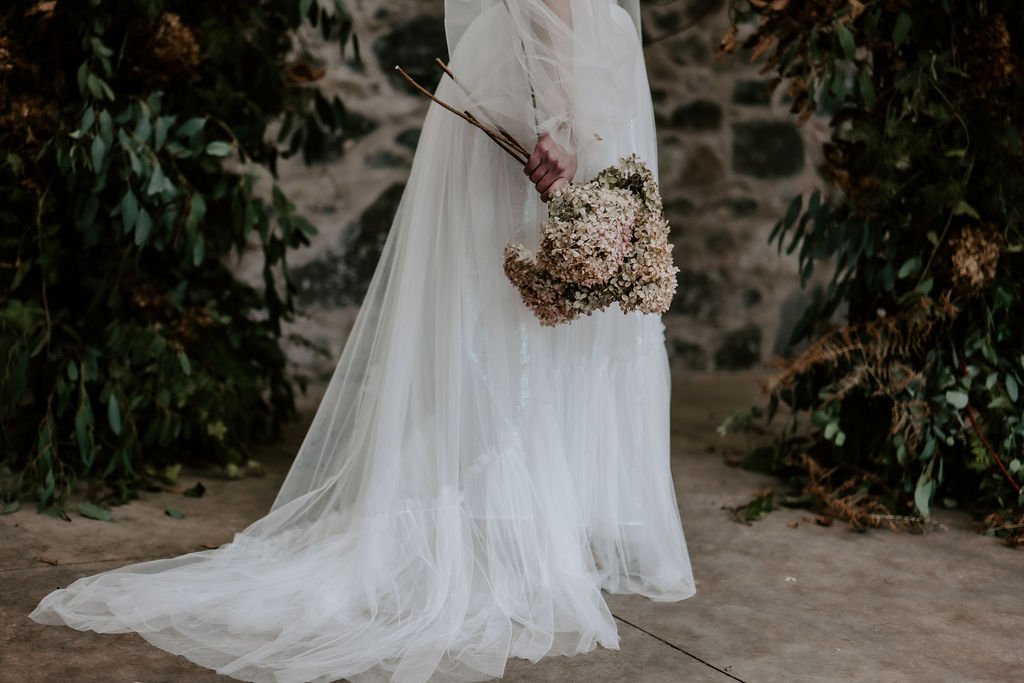 Long white wedding dress with sheer fabric layers and long sleeves.