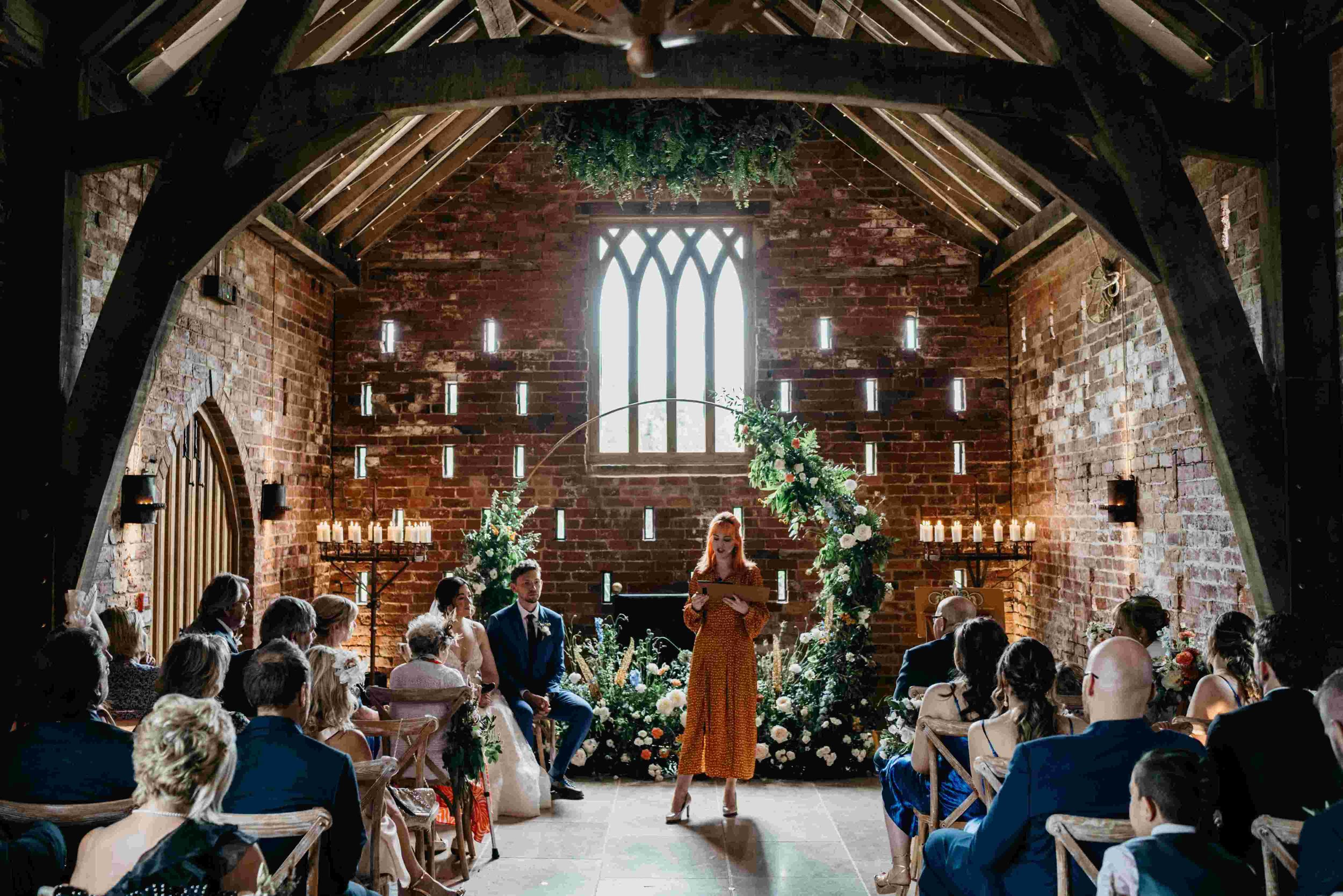  Photo by: David Boynton Photography  Modern wedding celebrant is holding the personalised wedding ceremony in a bright exposed brick room, with a vaulted ceiling and exposed wooden beams. The bride and groom are sat facing their wedding guests to th