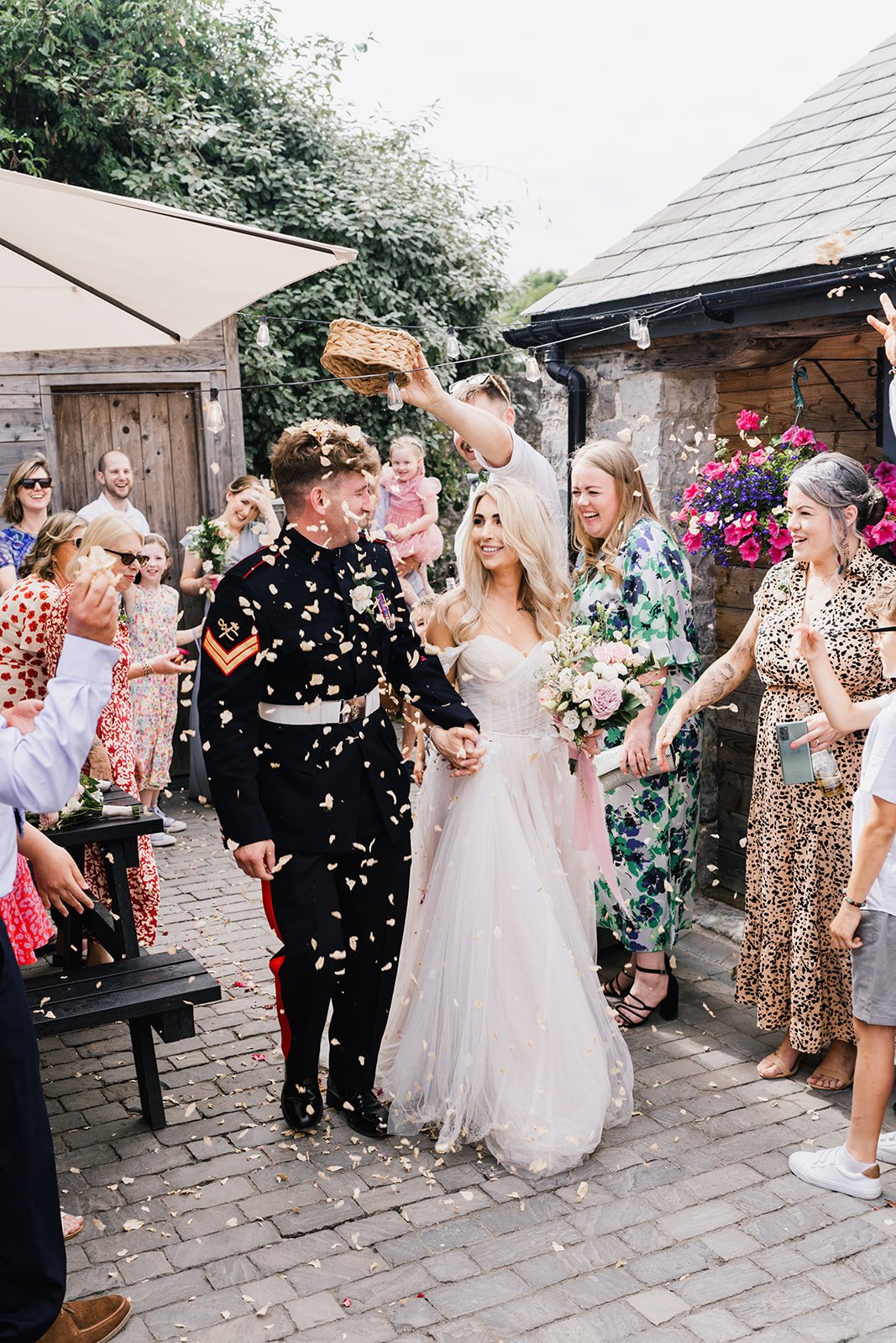  The bride is holding her whimsical, romantic floral bouquet as she walks holding hands with the groom through a shower of confetti, thrown by their wedding guests who are lining the path outside.   Photo by: Oliver Rees Photography 