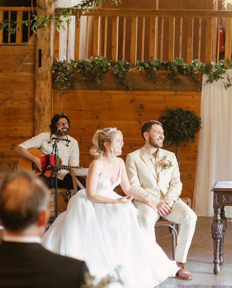  Acoustic guitarist is creating the atmosphere during the wedding ceremony as he plays the guitar and sings whilst sitting behind the bride and groom.   Photo by Bullit Photography 