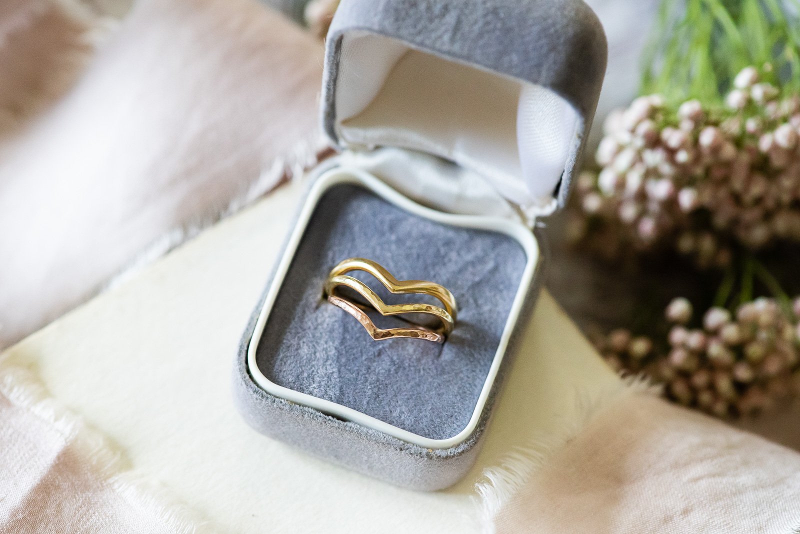  Three handmade, narrow wishbone wedding bands in gold, hammered gold and silver displayed in a box.   Photo by: Fiona Kelly 