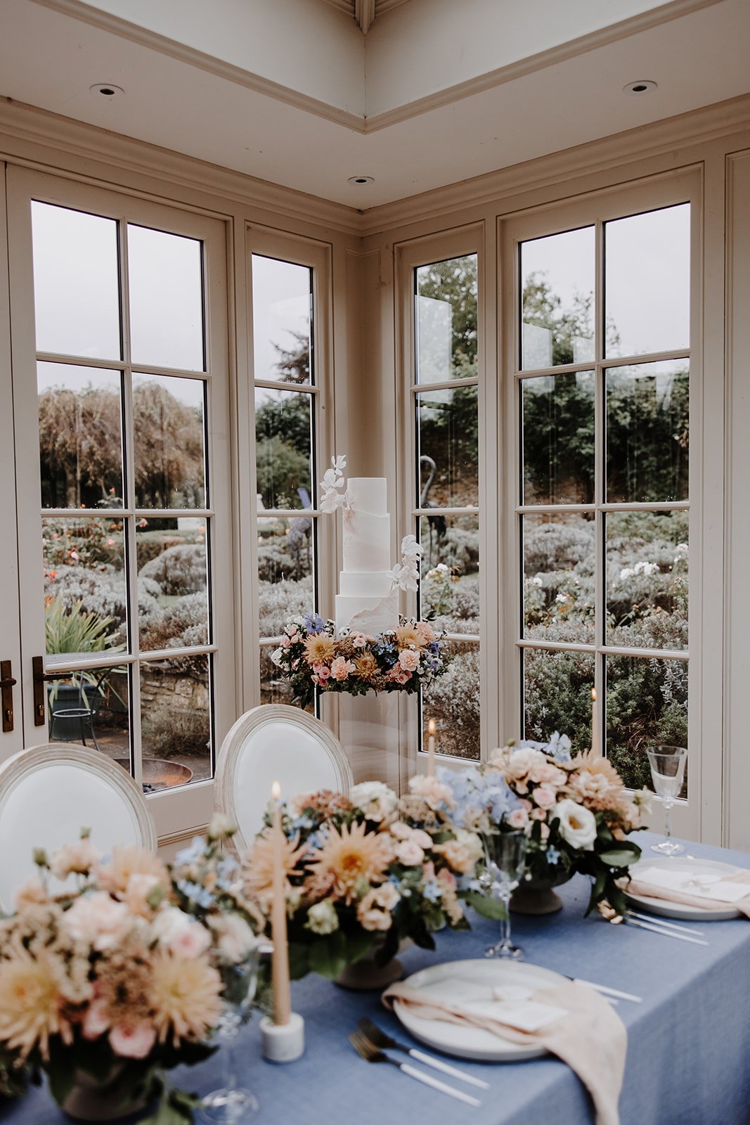  A still of a beautiful wedding breakfast table with table florals and the wedding cake on a stand behind, ready to be brought to life by wedding content creator.  Photo by: Megan Melissa Photography 
