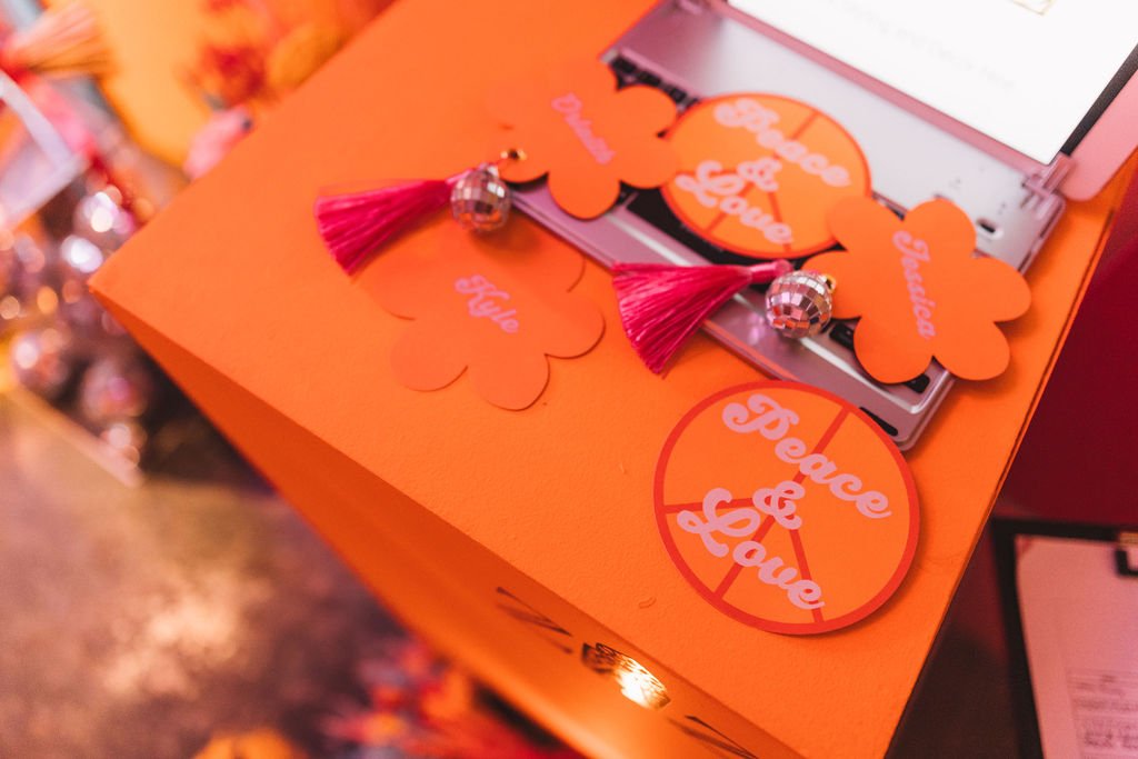  Some flower-shaped, orange, and pink place settings at The Un-Wedding Show featuring pink tassels and tiny disco balls. 