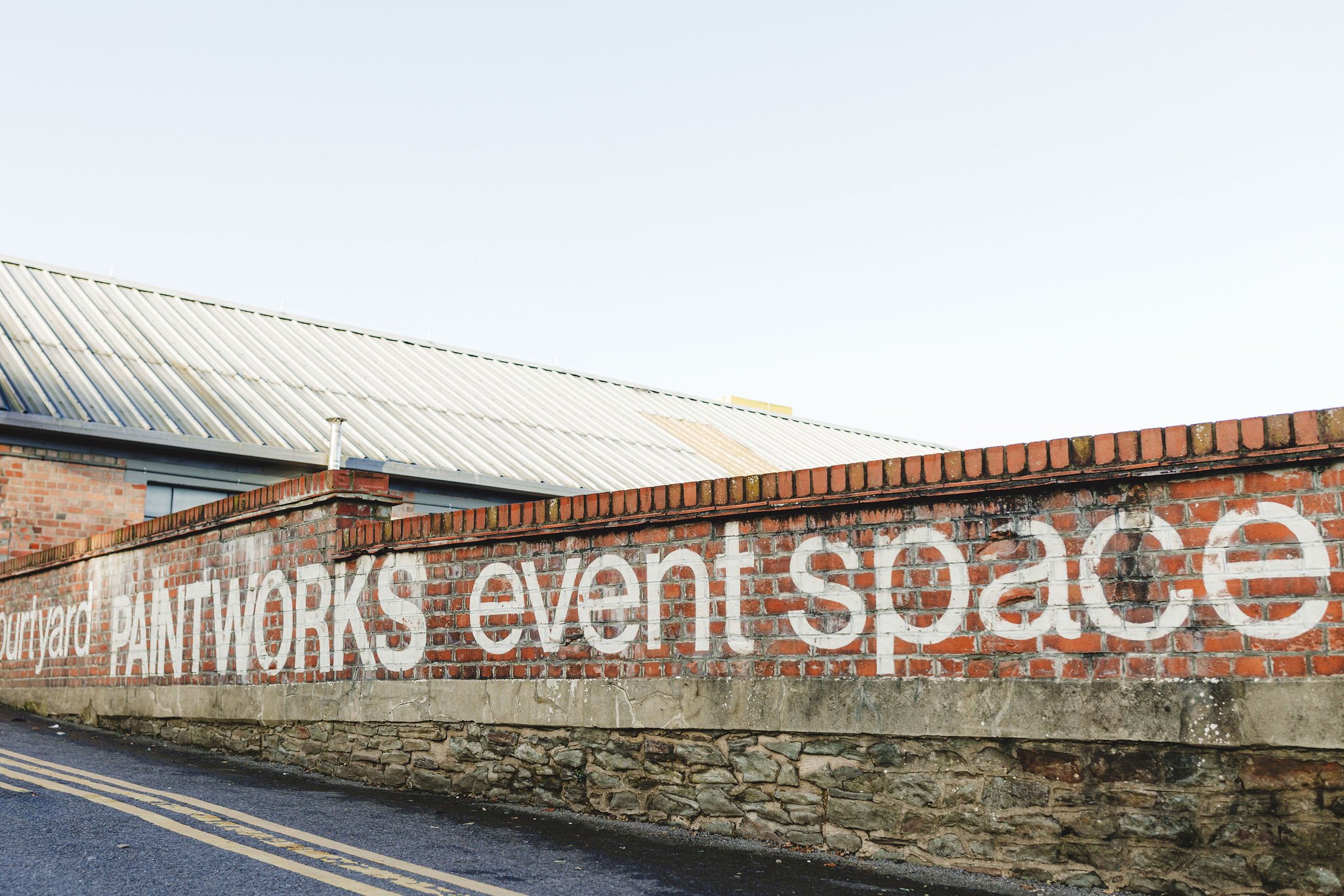  PAINTWORKS event space painted in white on exposed brick wall. 