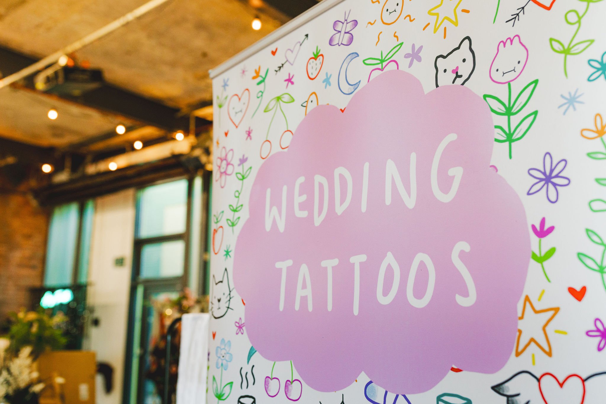  WEDDING TATTOOS sign surrounded by inspiring tattoo illustrations at Alice Green’s stand at TUWS Bristol. 