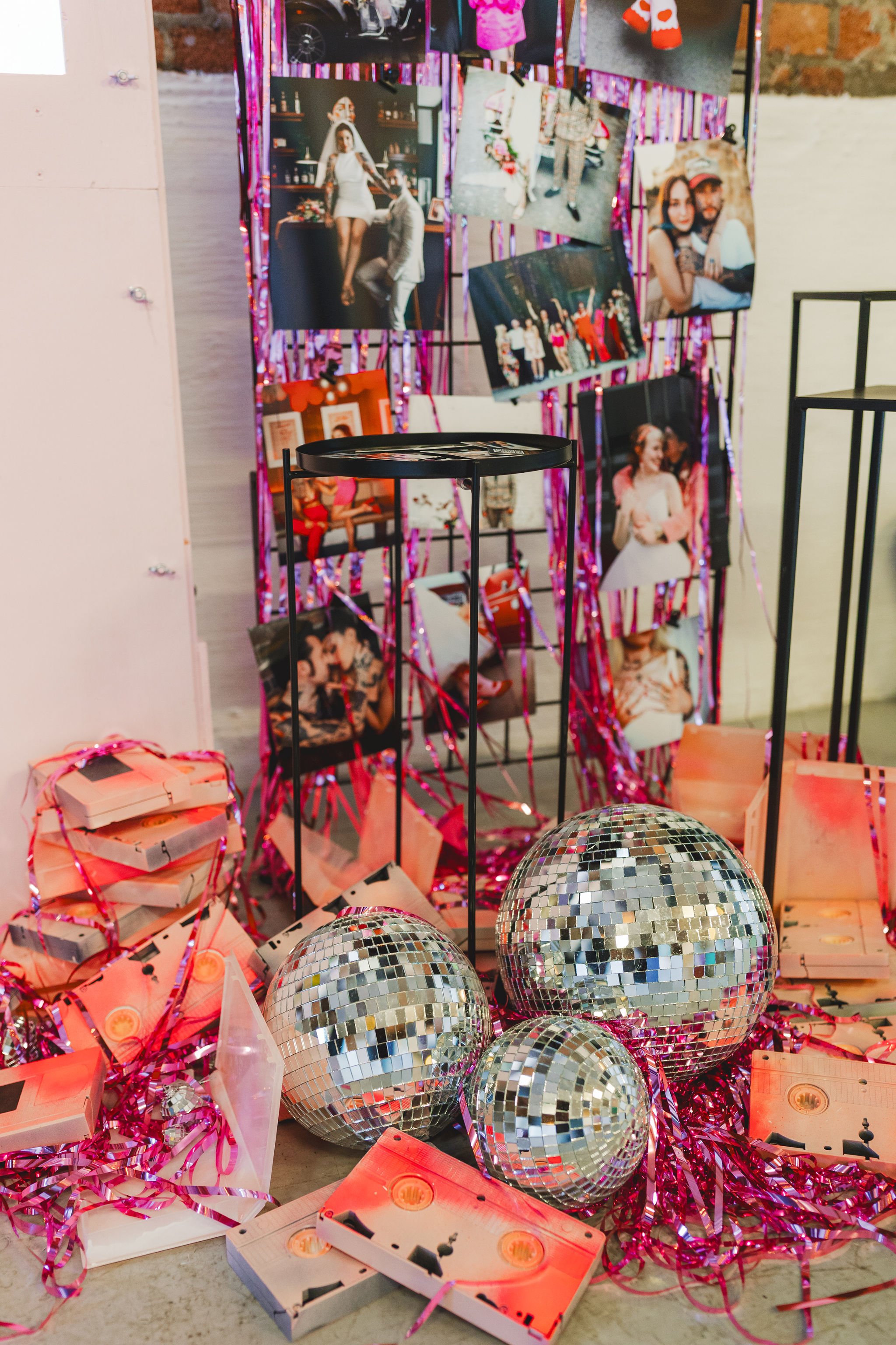  Disco balls and VHS tapes spay painted pink sit amongst pink steamers and photos at Costa Sisters stand at The Un-Wedding Show Bristol. 