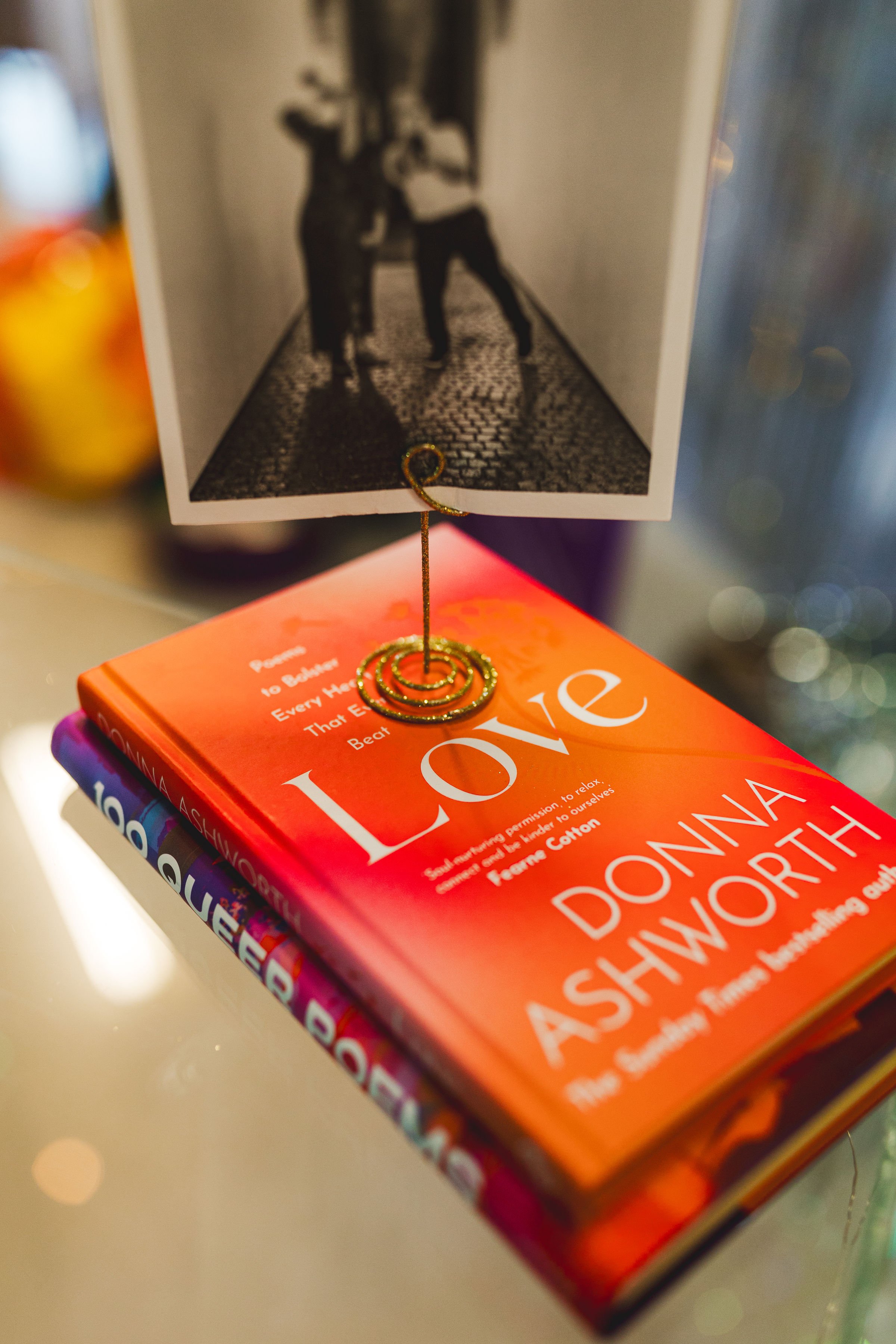  A black and white photo on a mini stand displayed on top of a couple of books, the top one has LOVE as the title. 