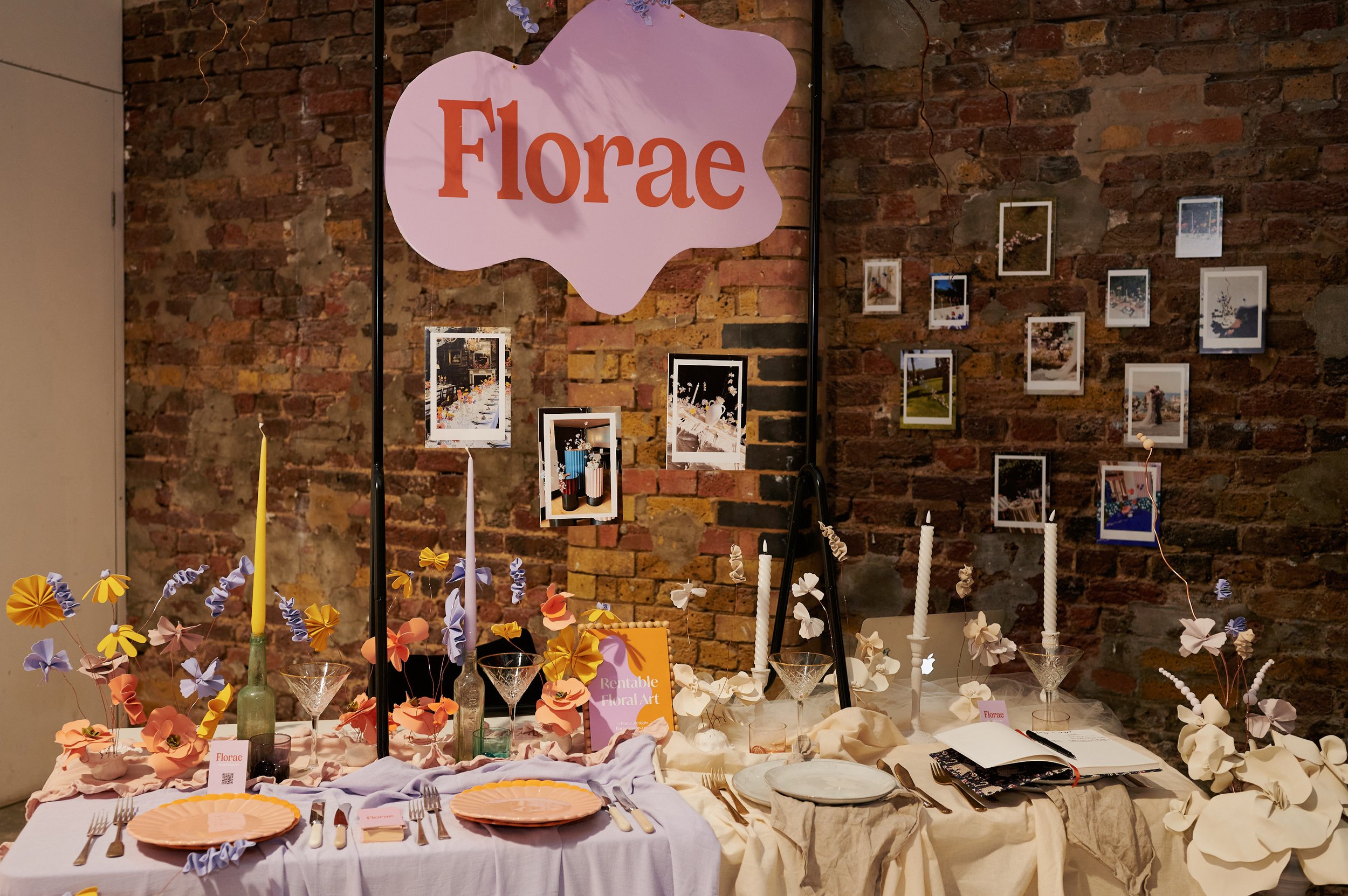  A pretty tablescape with a lilac and orange sign aboe it that says FLORAE. The table is half colourful/half neutral. 