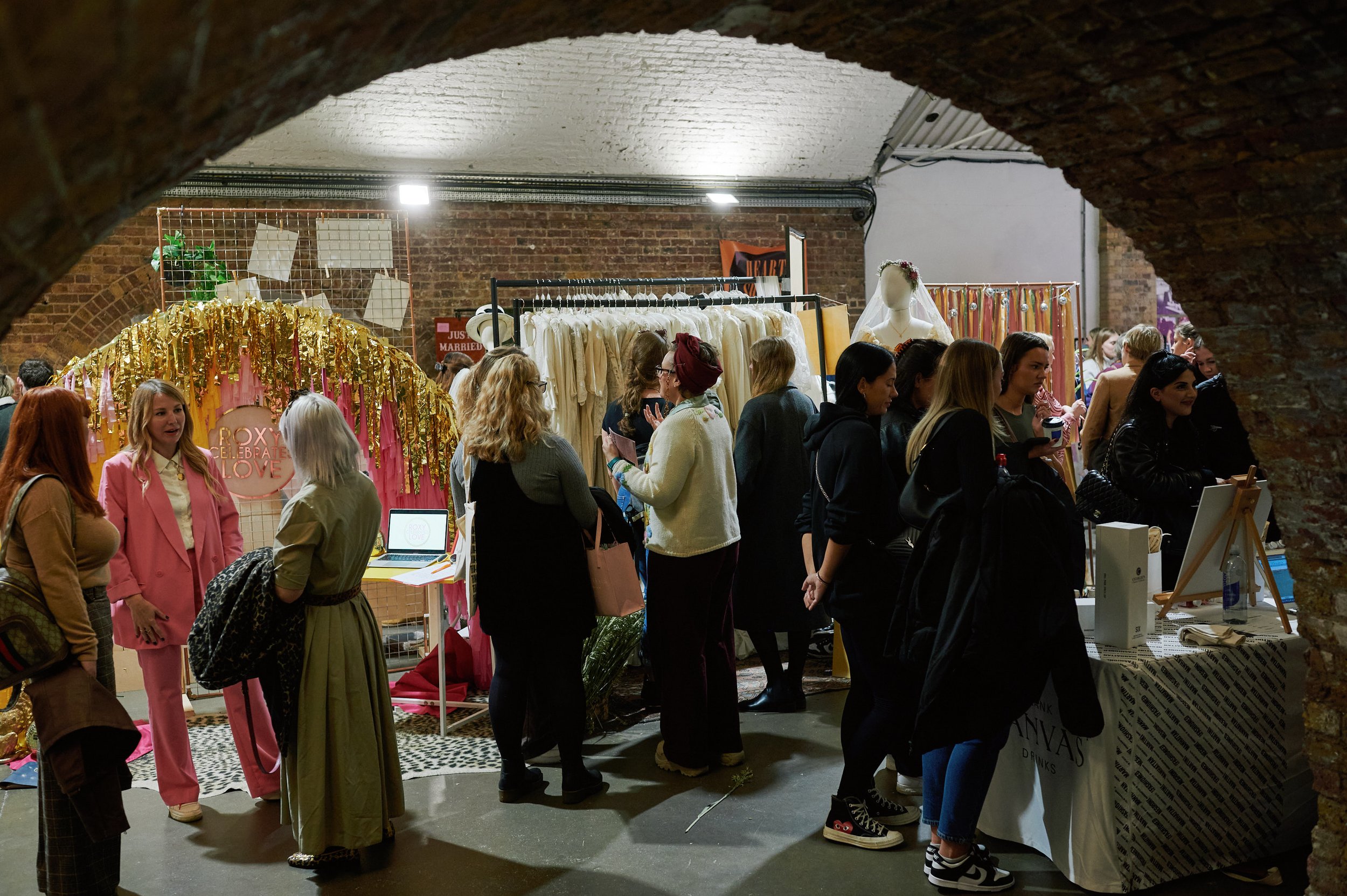  A photo taken through the arch that links studio 1 and 2 at The Un-Wedding show, Shoreditch Studios. You can see lots of people chatting to suppliers. 