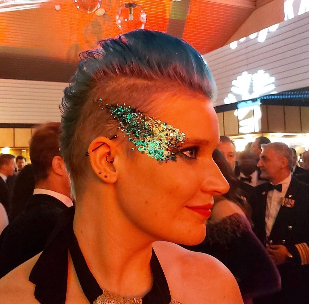  A side profile of a wedding guest who has had a glitter thunderbolt applied around their eye by the glo artists as the evening wedding entertainment. 
