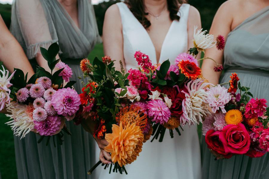  An upclose image of the wedding party’s modern cascade bouquets. Different blooms have been used to make up the various individual bouquets and look sensational together with the clash of bright pink and orange wedding florals.  The fun wedding bouq