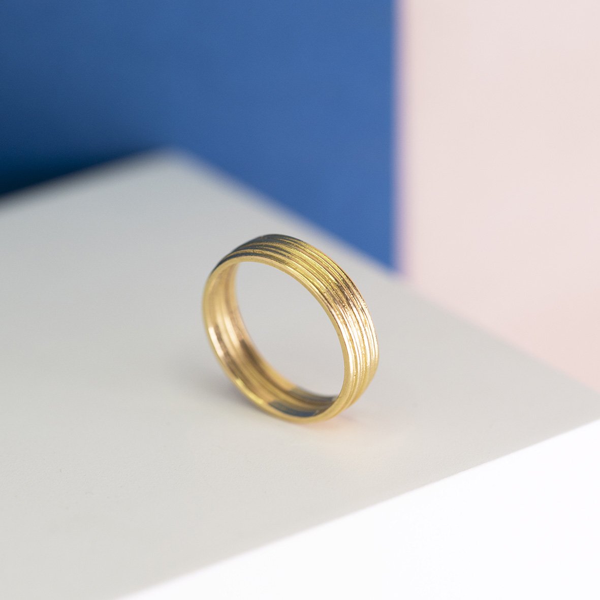  A modern, stylish, plain gold wedding band with textured lines etched into it. 