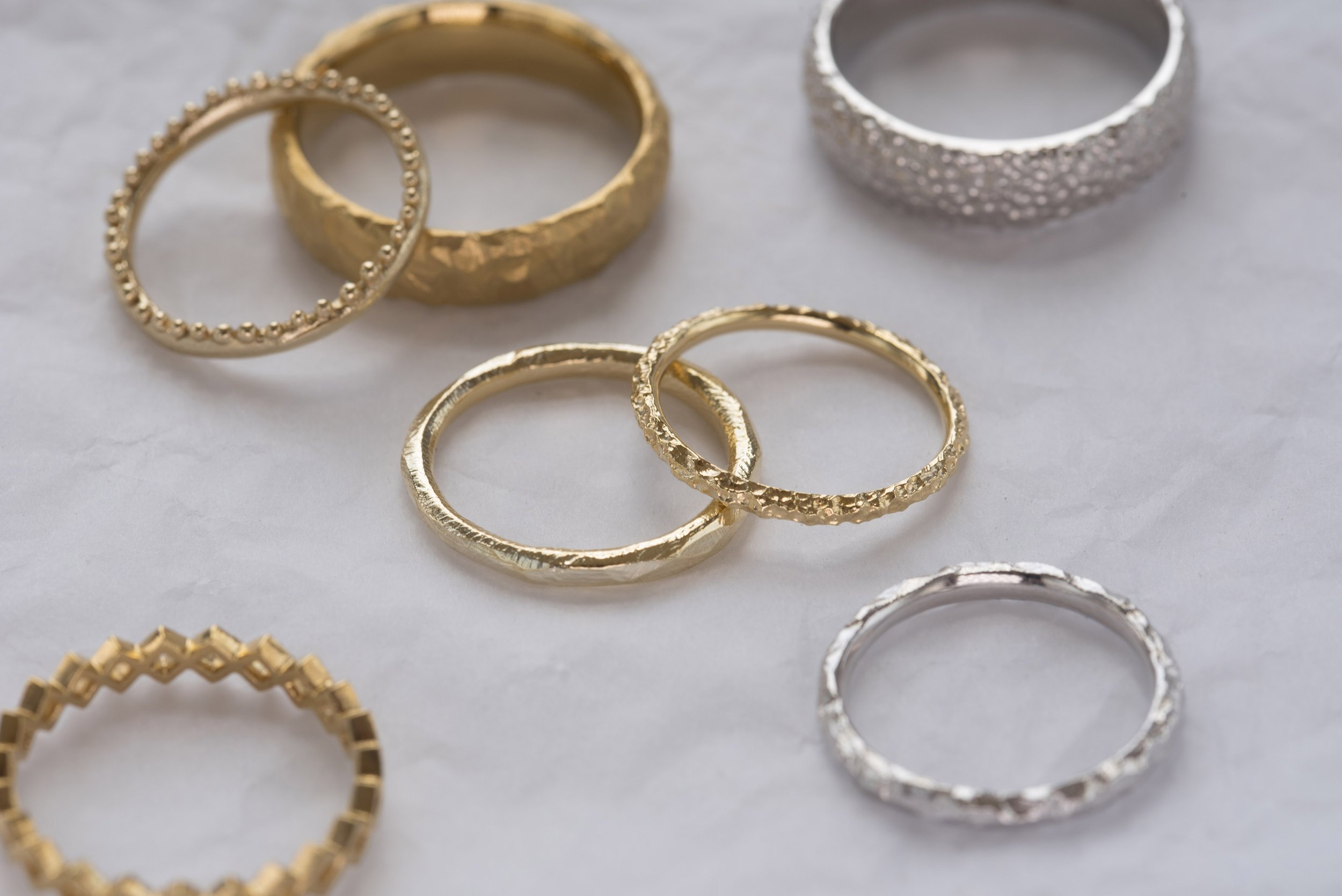  Various gold and silver wedding bands displayed in different thickness’, widths and textures. 