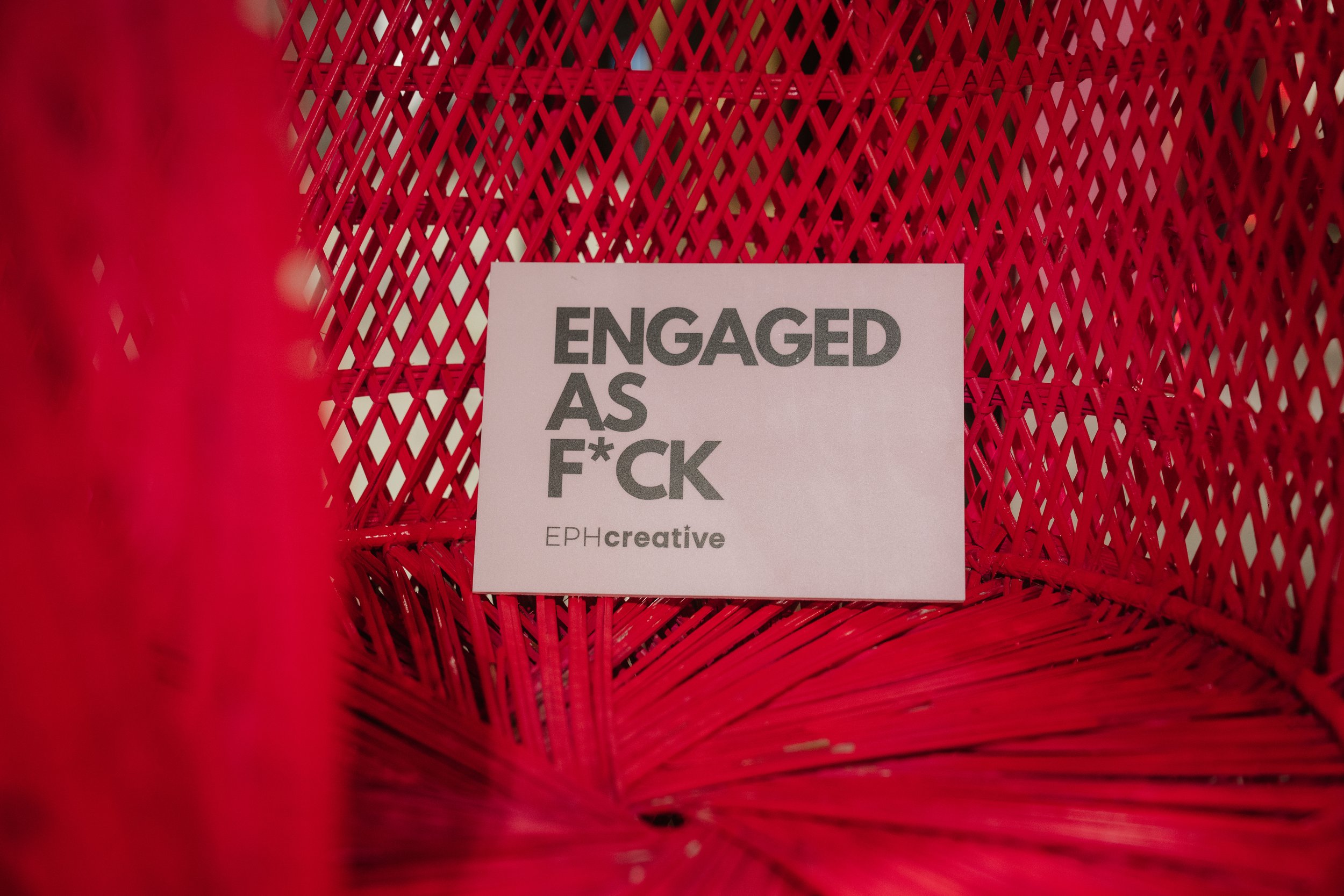  ENGAGED AS F*CK postcard showcased on a bright pink wicker wedding chair. 