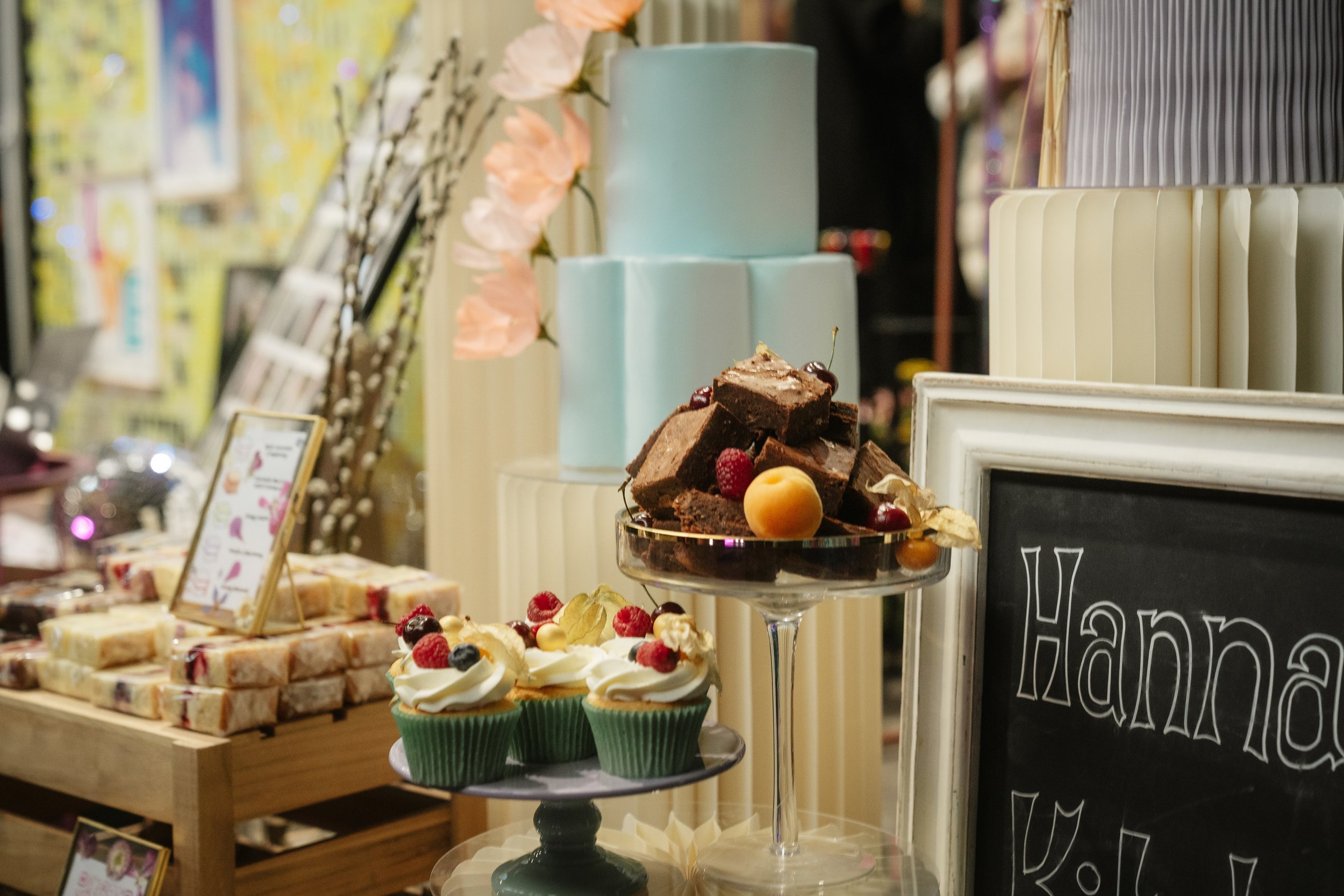 An image of Hannah’s Kitchen’s stand at The Un-Wedding Show where a selection of the bakes which can be produced are showcased including brownies and cupcakes that are created for weddings. 