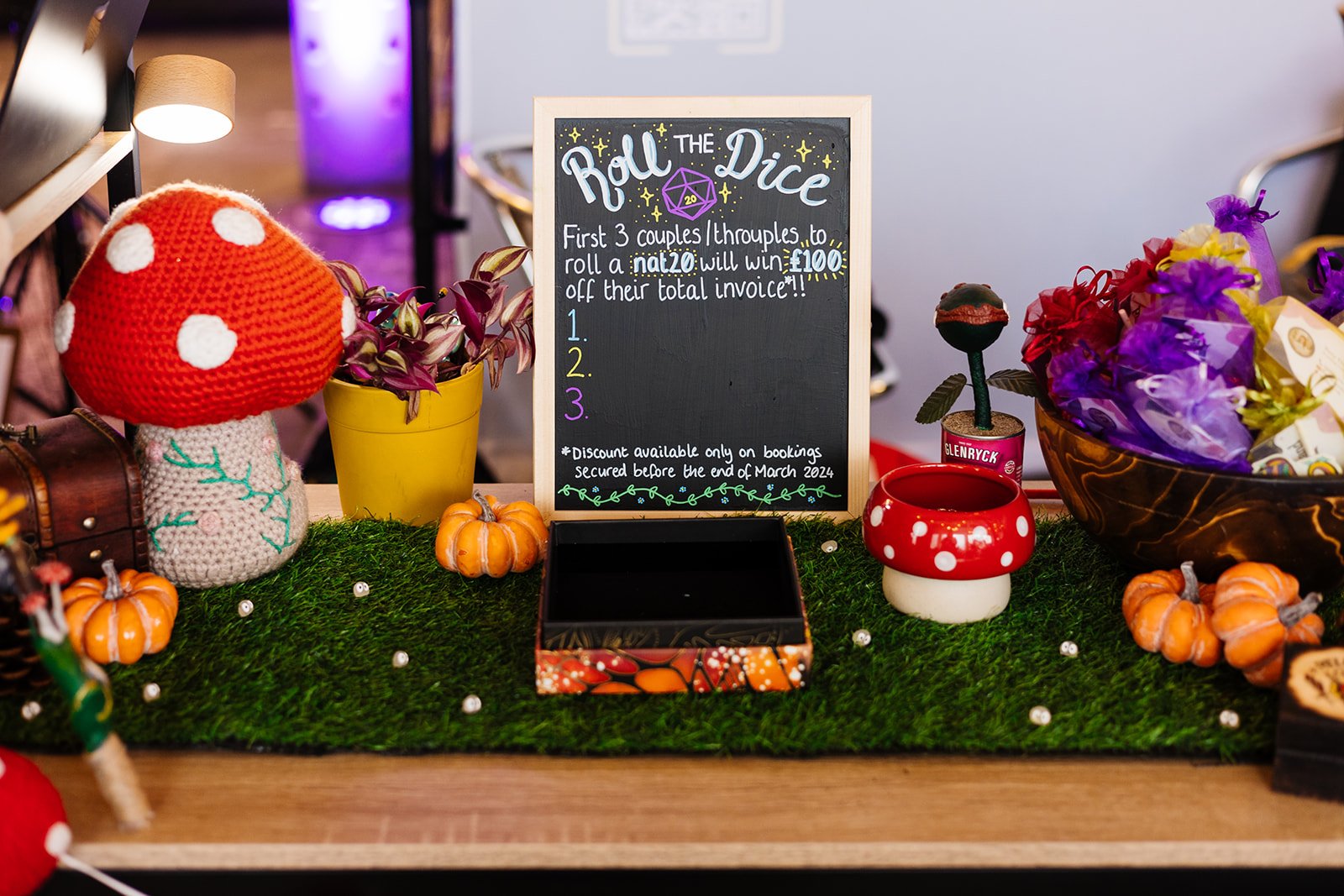  A knitted toadstool on a table that has a sign which says ‘Roll the dice’ 