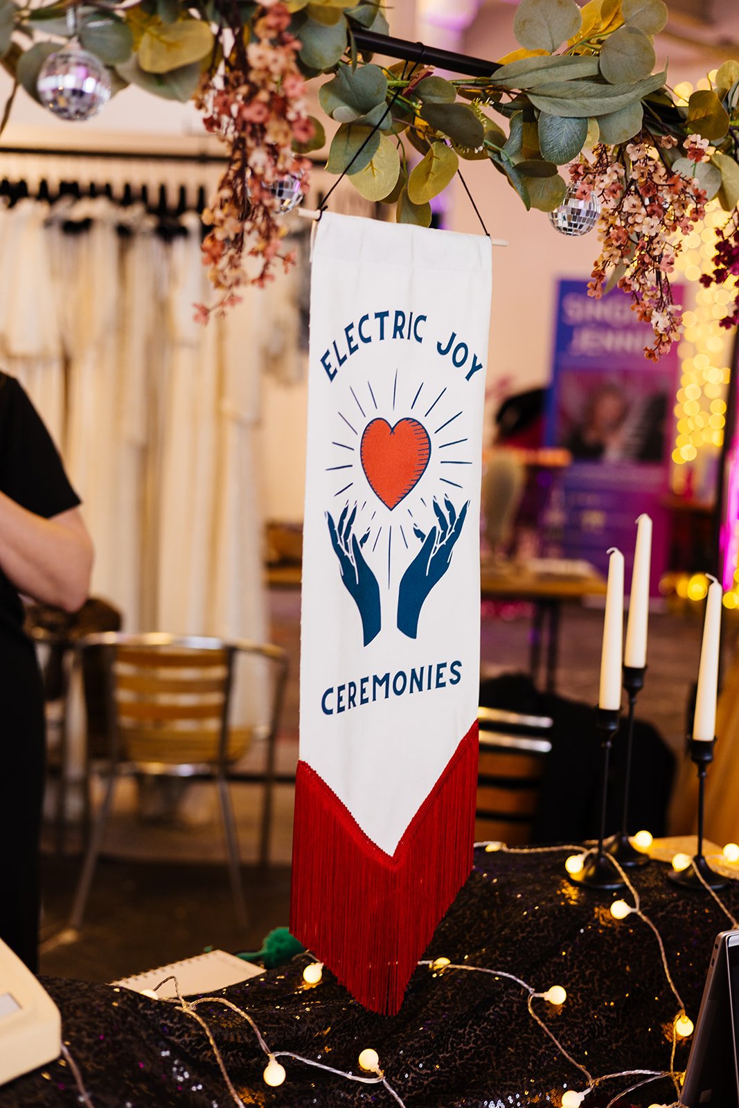  A handmade banner with the words ‘Electric Joy’ and 2 hands holding a red heart. 