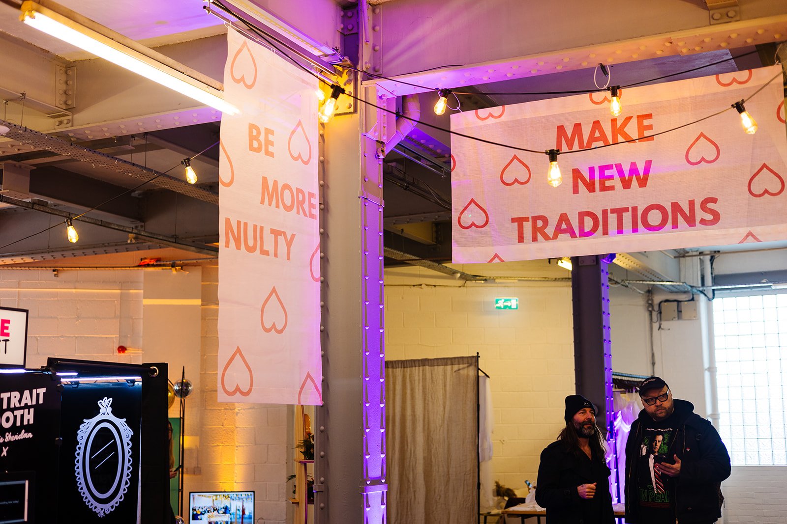  Red and pink banners at The Un-Wedding Show Sheffield. One says Be More Nulty and the other says Make New Traditions. 