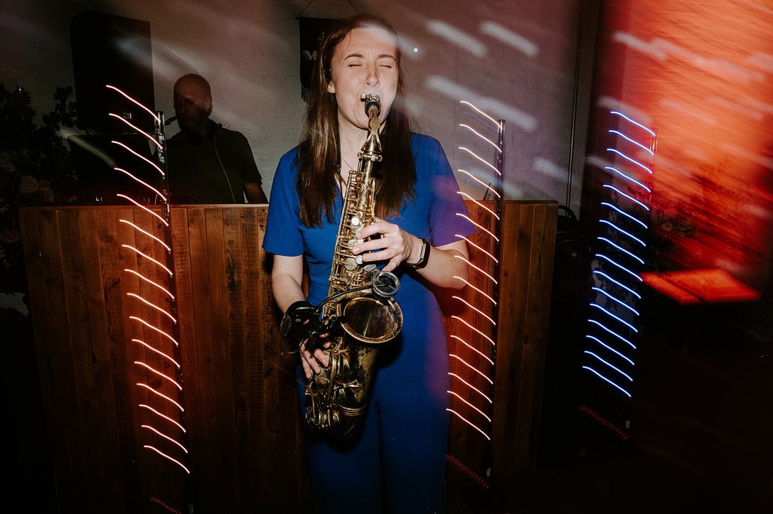 Evening musical entertainment. A solo sax being played surrounded by neons and lights at a wedding reception.