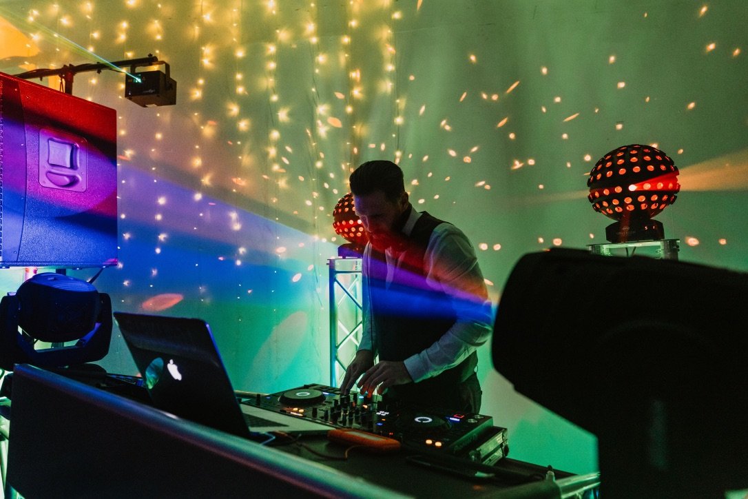 A wedding DJ with neon lights behind decks.