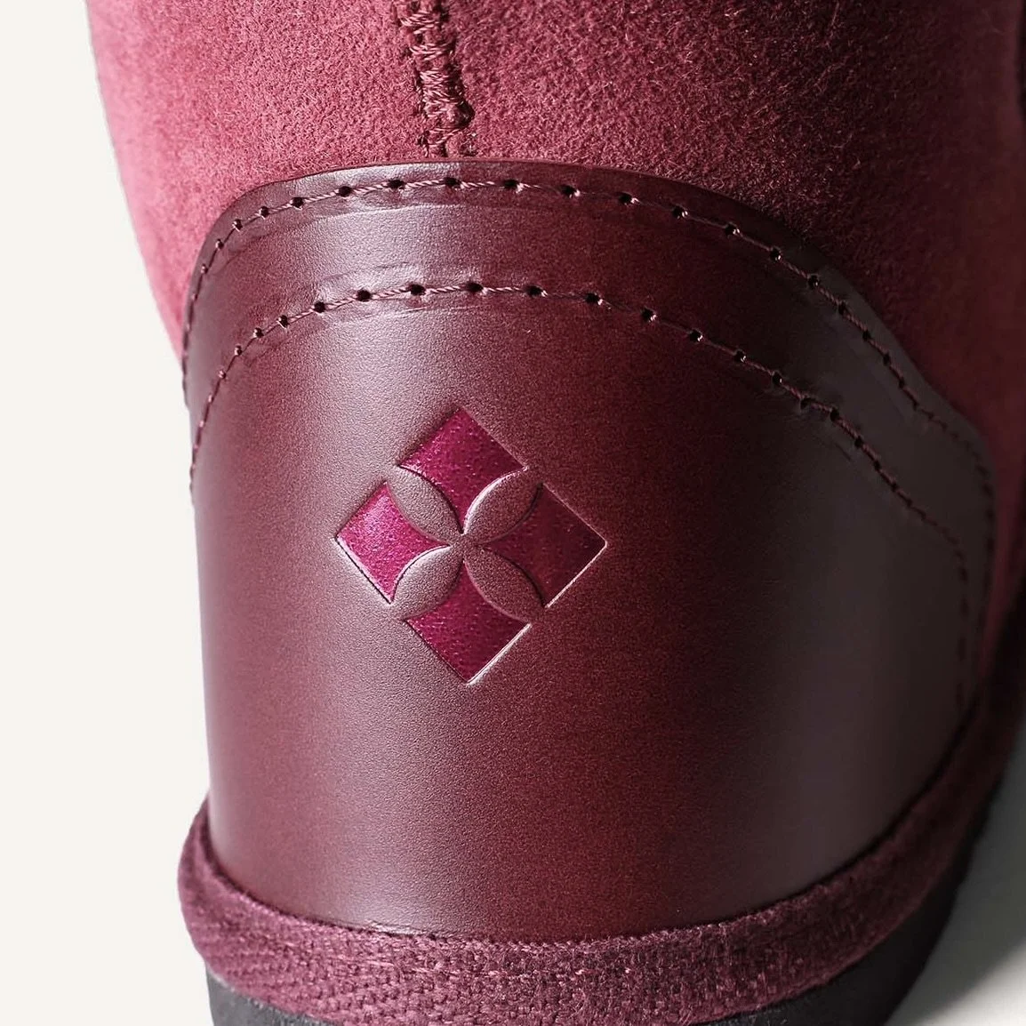 Close up of plum leather heel with metallic pink logo.