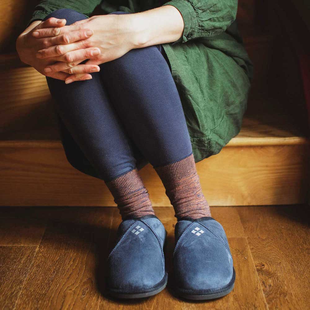 Woman wearing blue sheepskin slippers, sitting on a step.