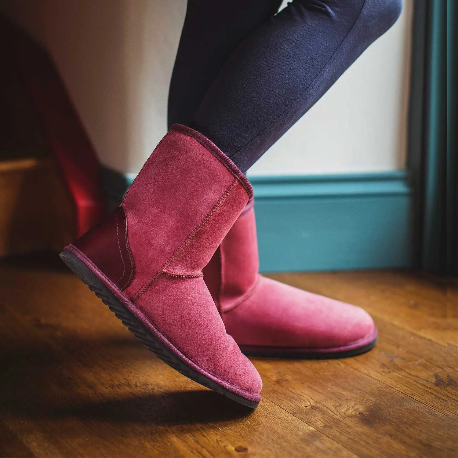**Person wearing pink sheepskin slipper boots indoors**