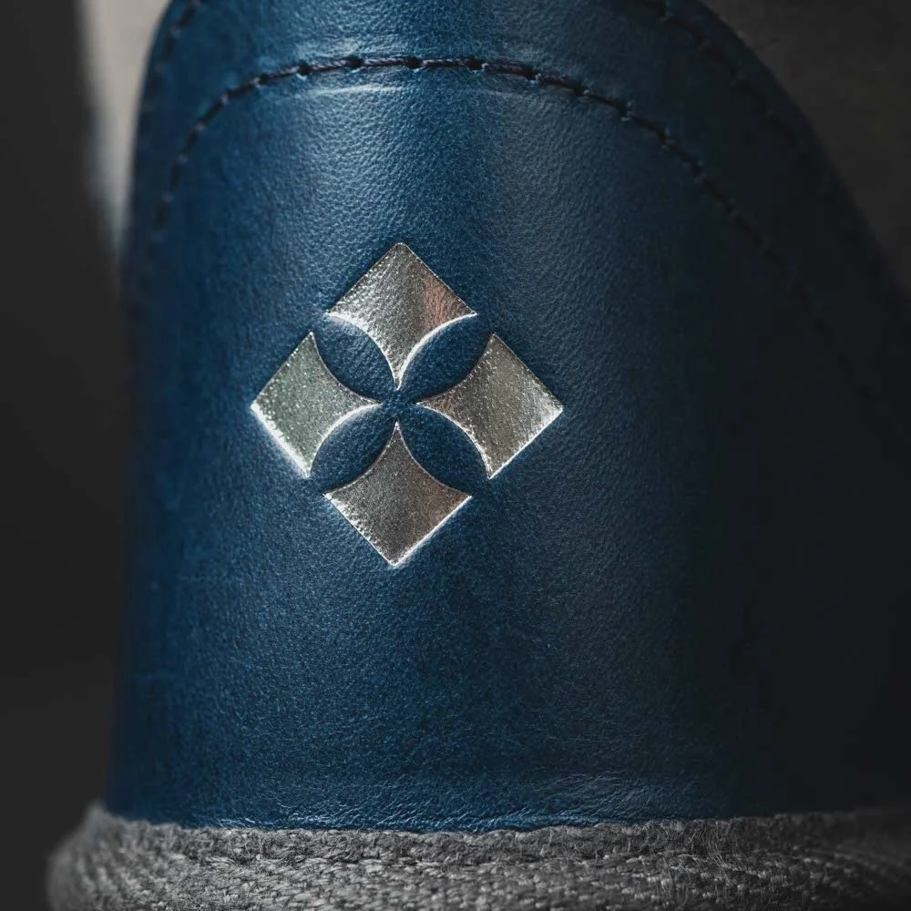 Close up of silver logo on teal leather.