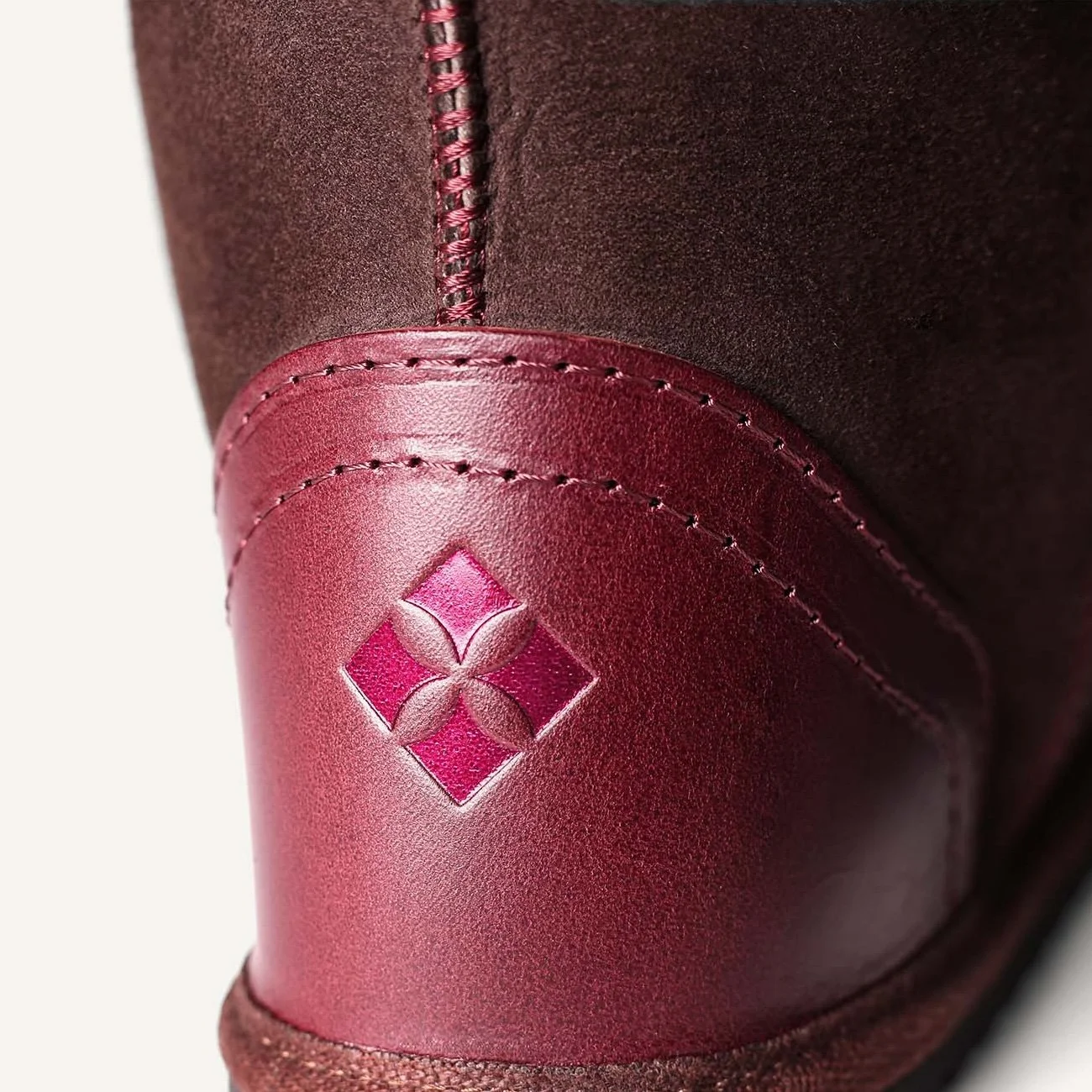 Close up of plum leather heel embossed with pink metallic logo.