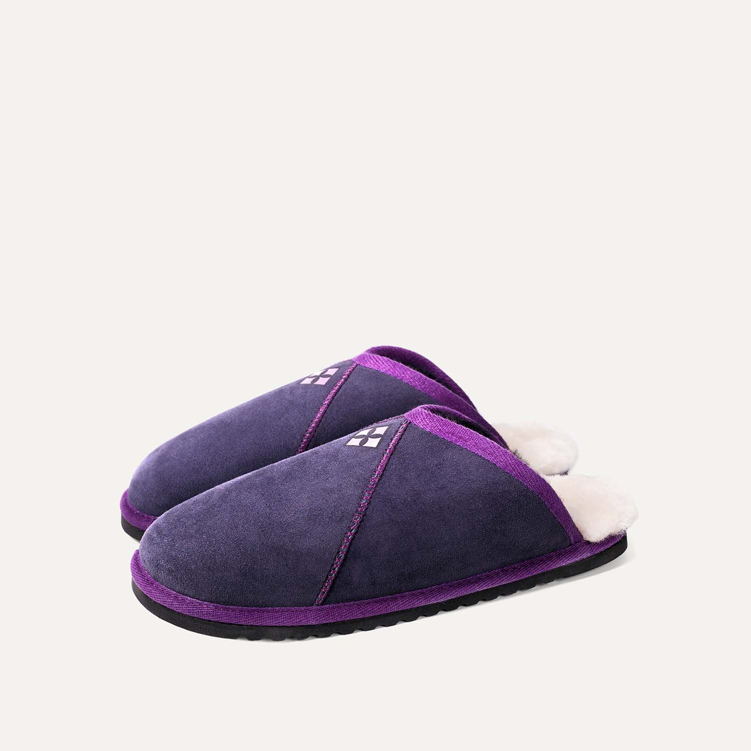 A pair of navy and purple sheepskin slippers.
