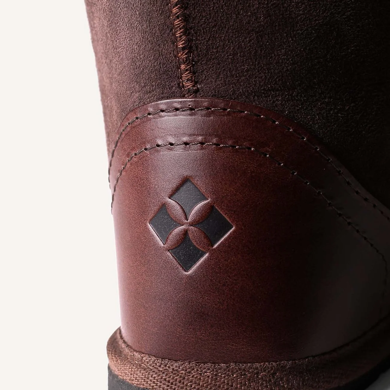 Close up of embossed X shaped logo on brown leather heel.