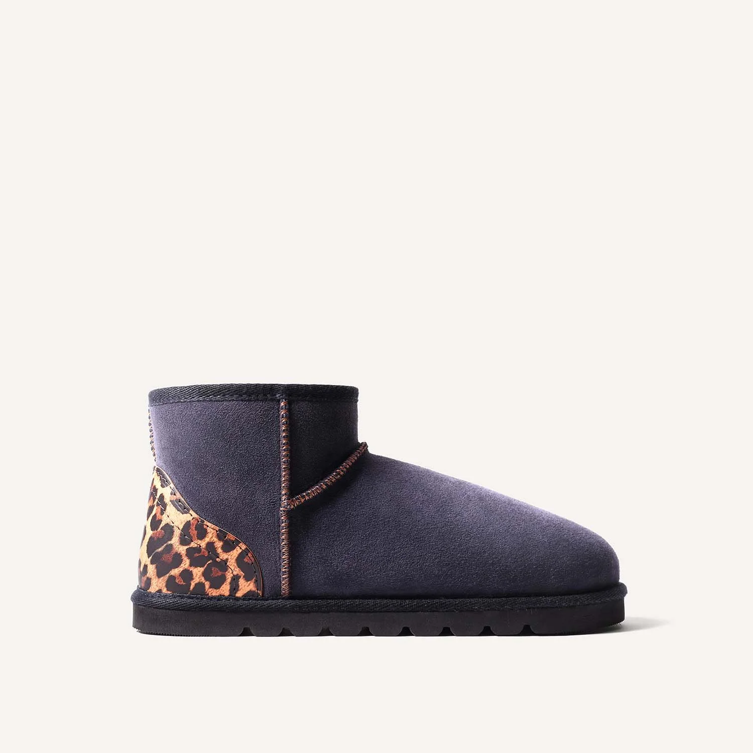 Side view of navy blue sheepskin boot with leopard print heel.