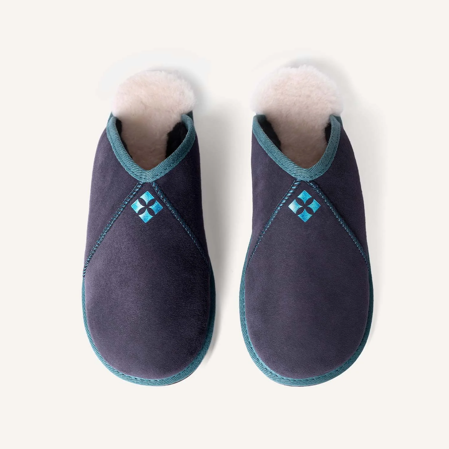 Navy blue and teal sheepskin slippers on a white background