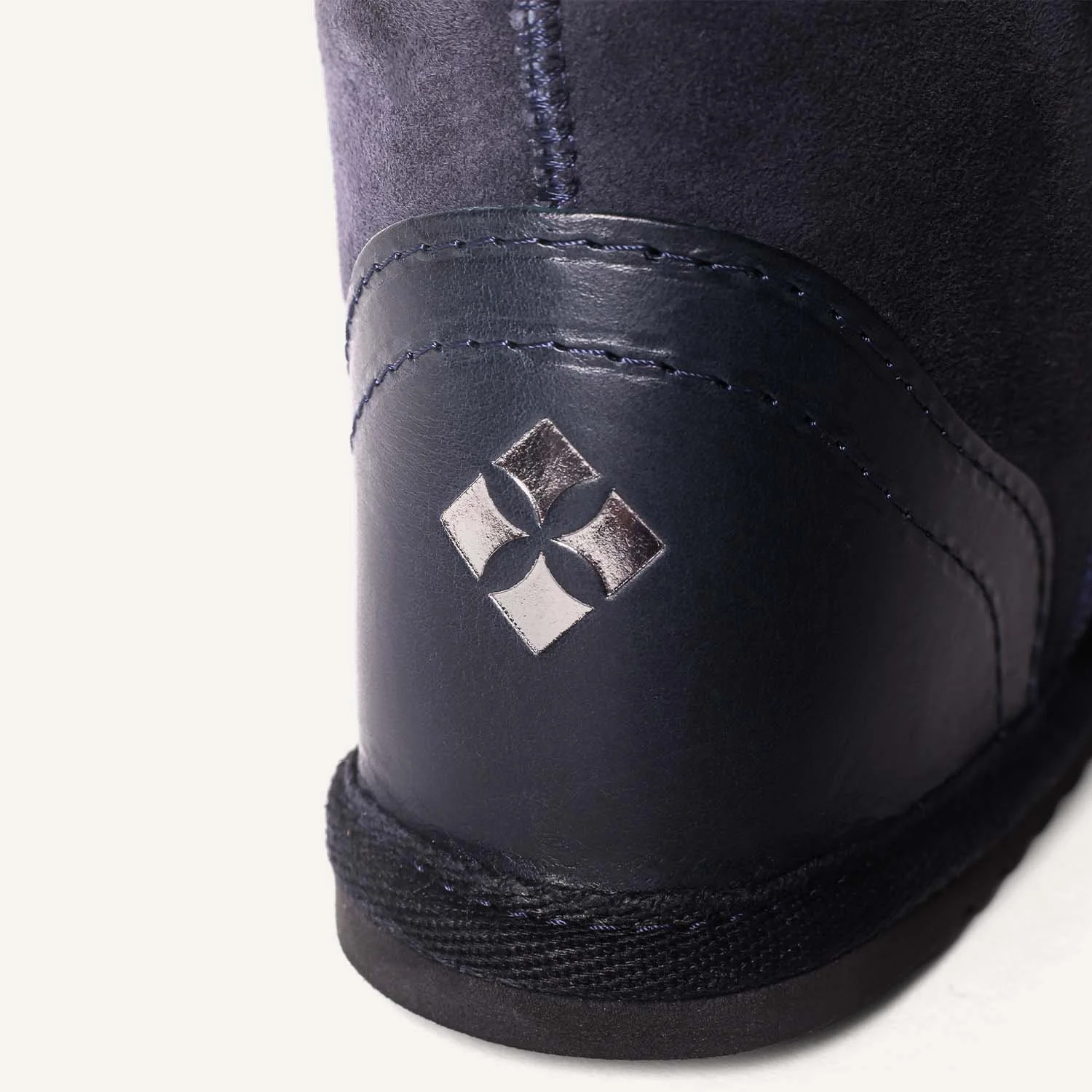 Close up of navy blue leather heel with embossed logo in silver.