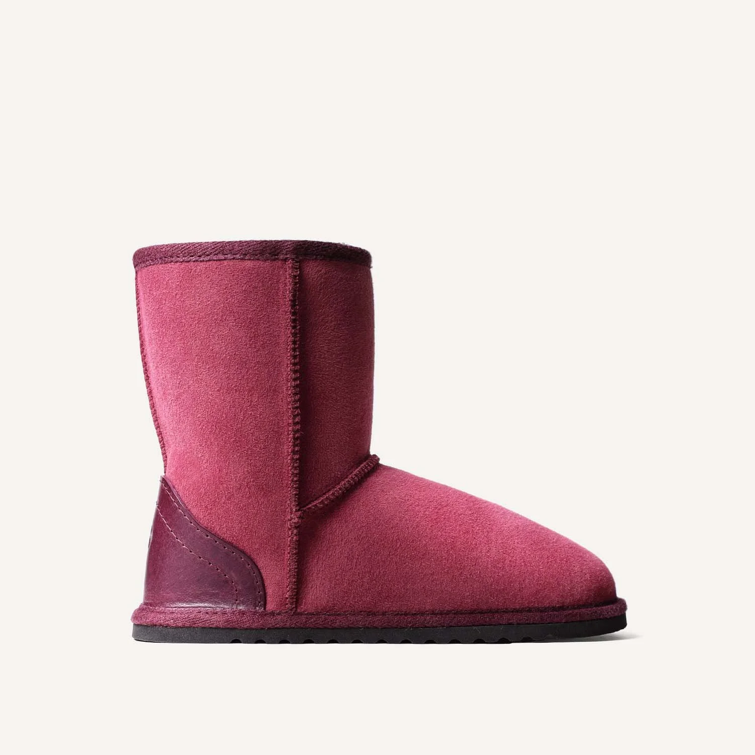 A single pink sheepskin slipper boot, side view.