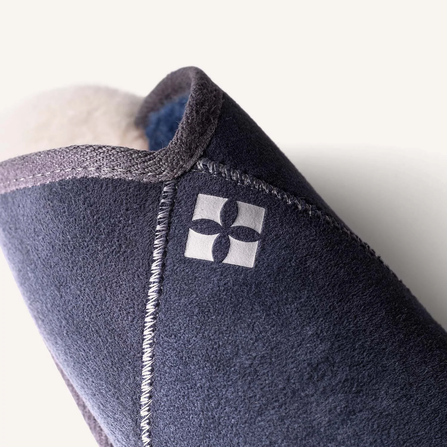 Clos eup of silver Xanthe Anna logo on blue sheepskin slipper.