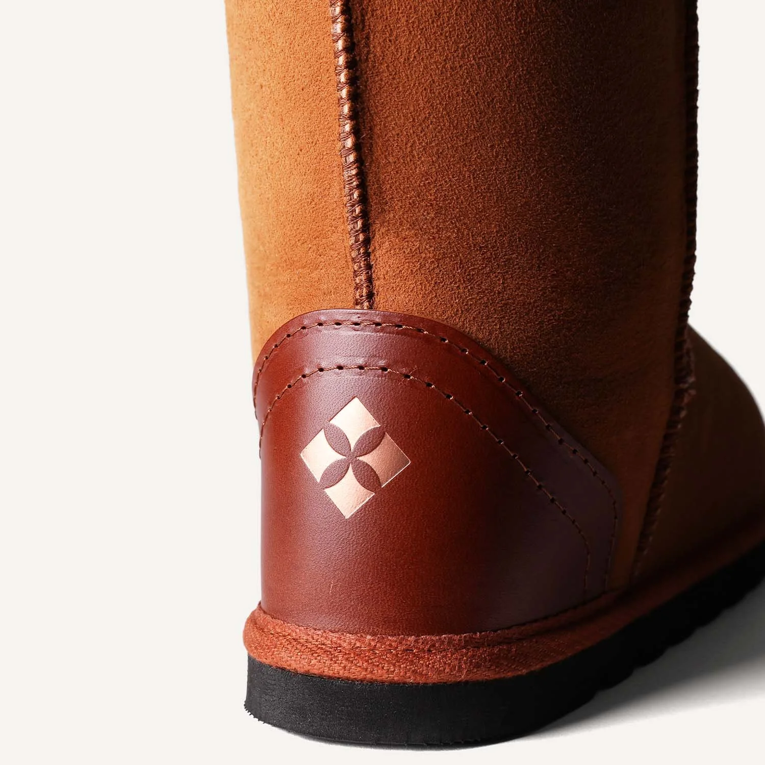 close up of veg-tan leather heel in tan with embossed geometric logo in copper.